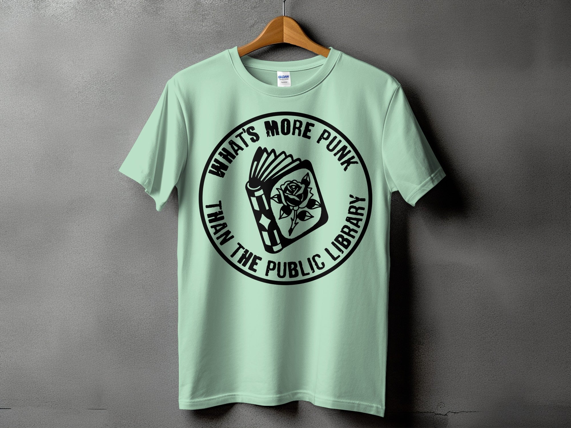 Light green t-shirt with circular text and an open book with a rose graphic.