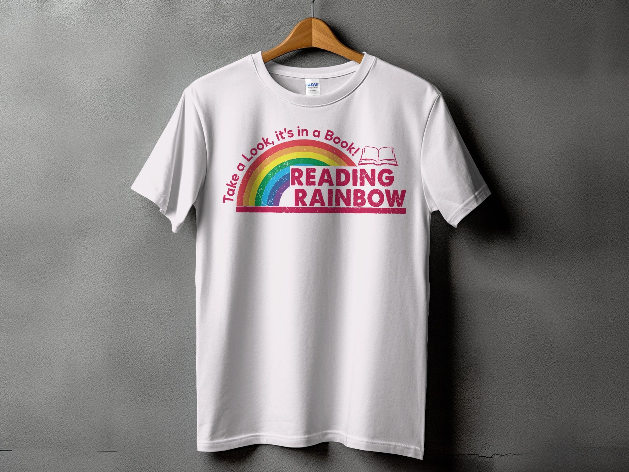 White t-shirt with rainbow graphic and text "Take a Look, it's in a Book! READING RAINBOW".