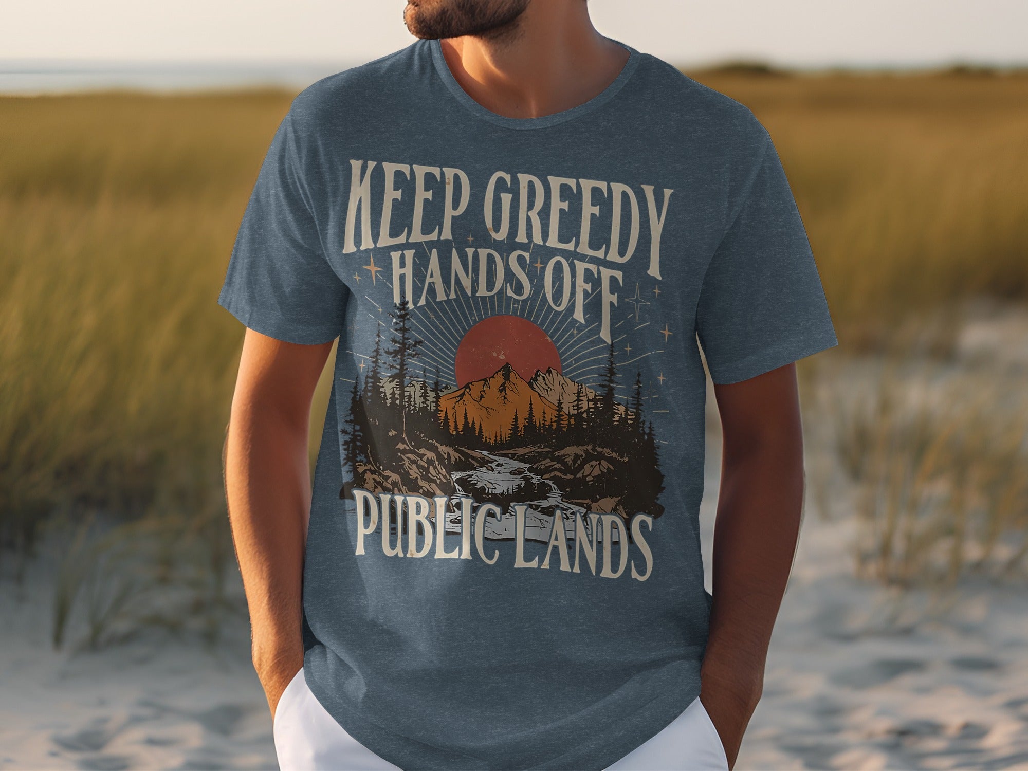 Blue t-shirt with text "Keep Greedy Hands Off Public Lands" and nature graphic.