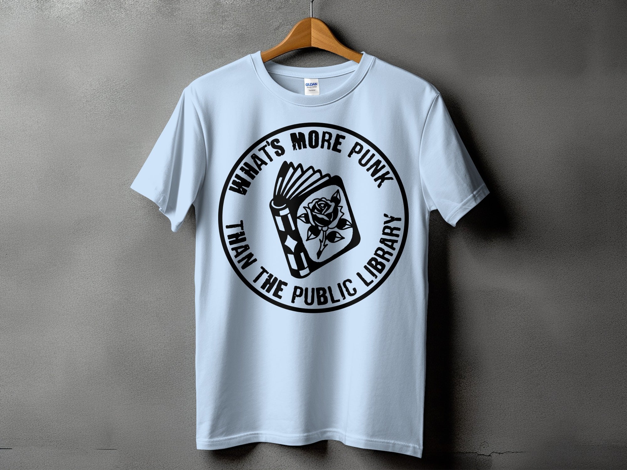 Light blue t-shirt with a circular black graphic of an open book and rose, text "What's more punk than the public library".