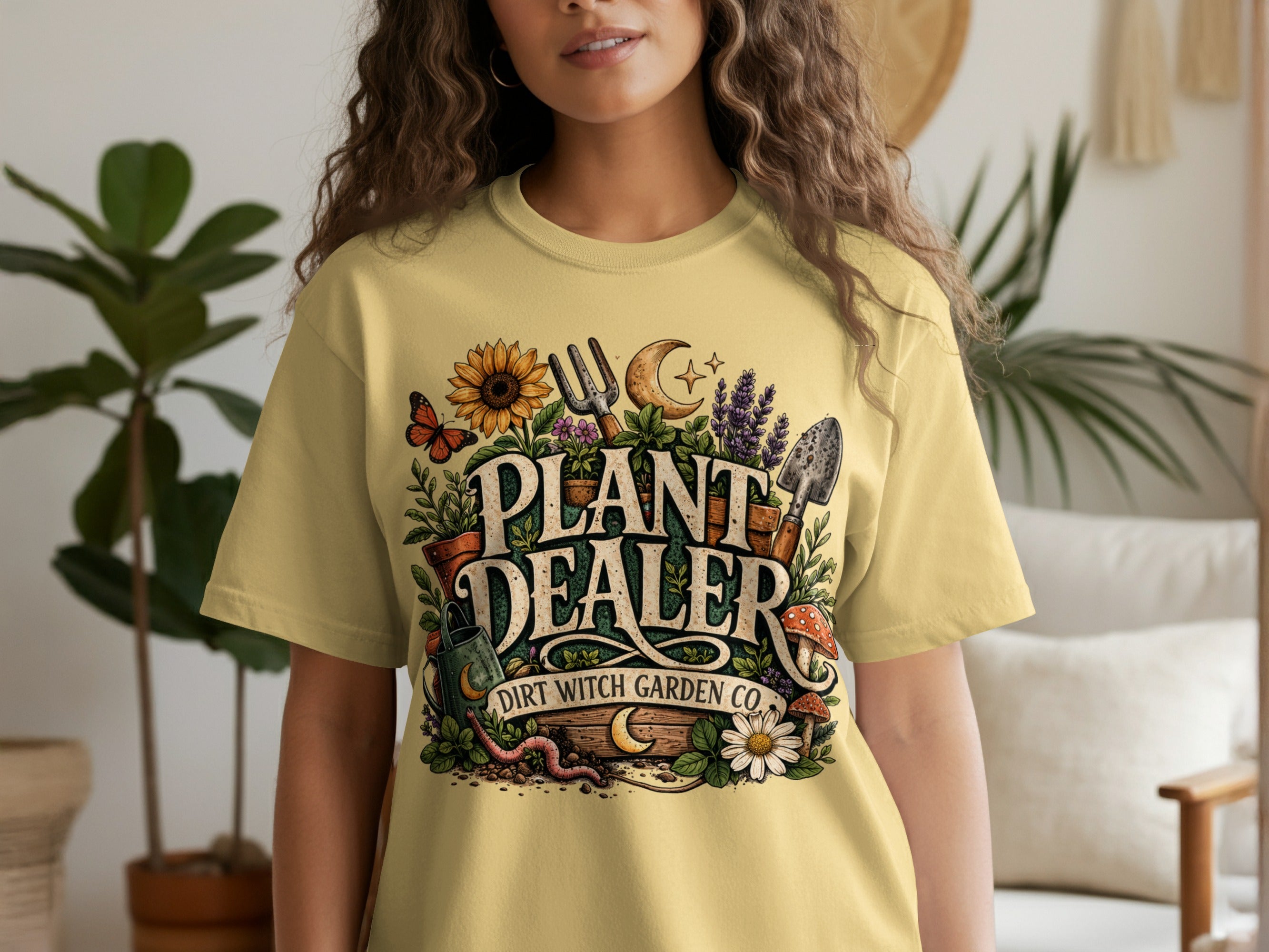 Yellow t-shirt with "Plant Dealer Dirt Witch Garden Co." graphic featuring plants, tools, and insects.