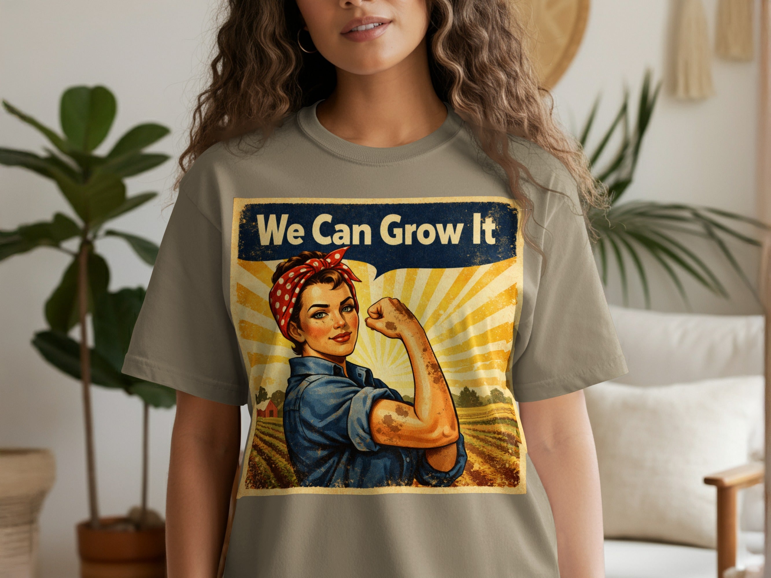 T-shirt graphic of Rosie the Riveter flexing, with text "We Can Grow It" over a farm scene.