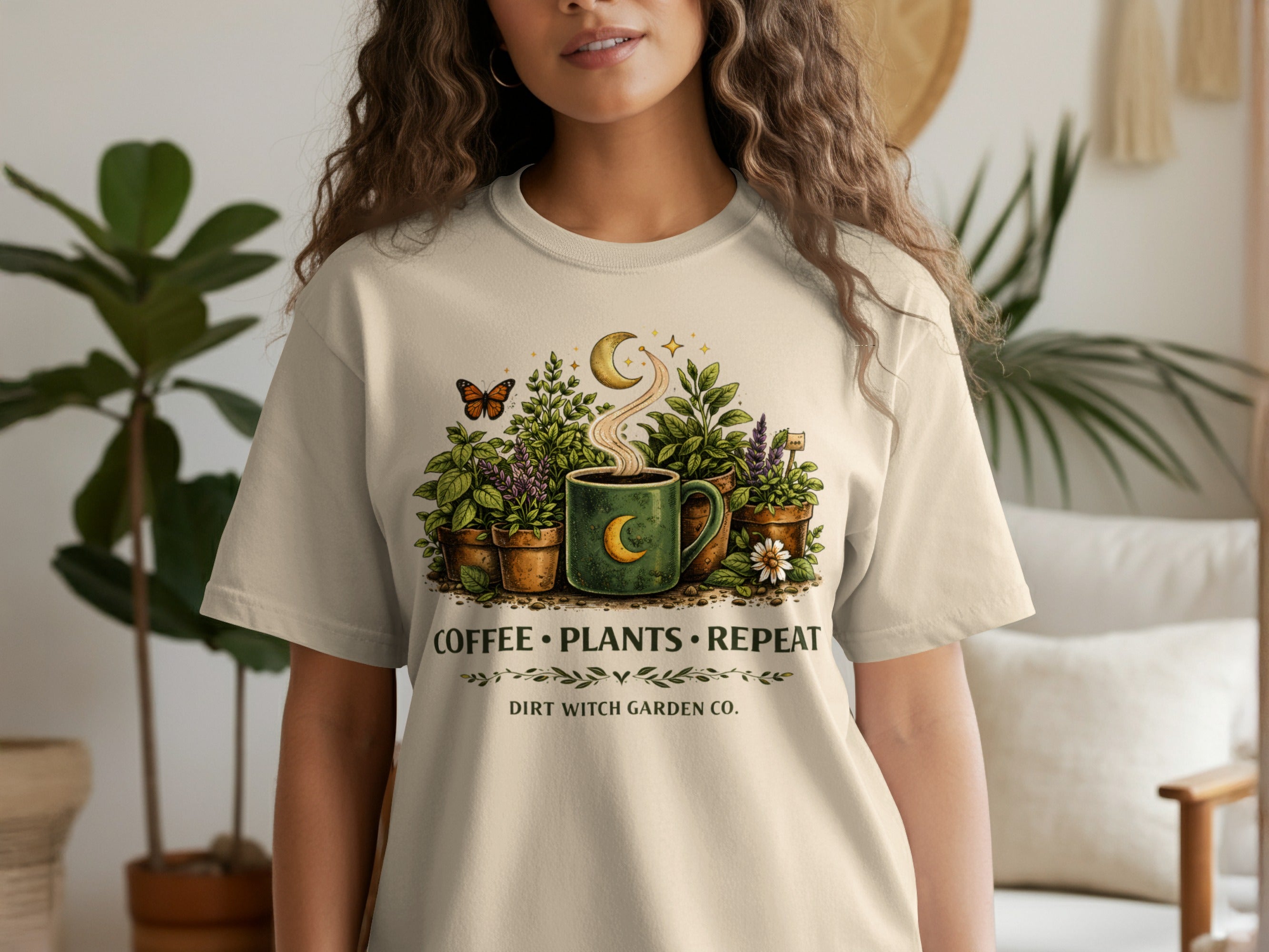 Graphic tee with coffee cup surrounded by plants, moon, and butterfly, reads "Coffee Plants Repeat Dirt Witch Garden Co."