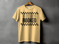 Light yellow t-shirt with black text that reads "MY TBR TOLD ME TO TELL YOU I'M BOOKED".