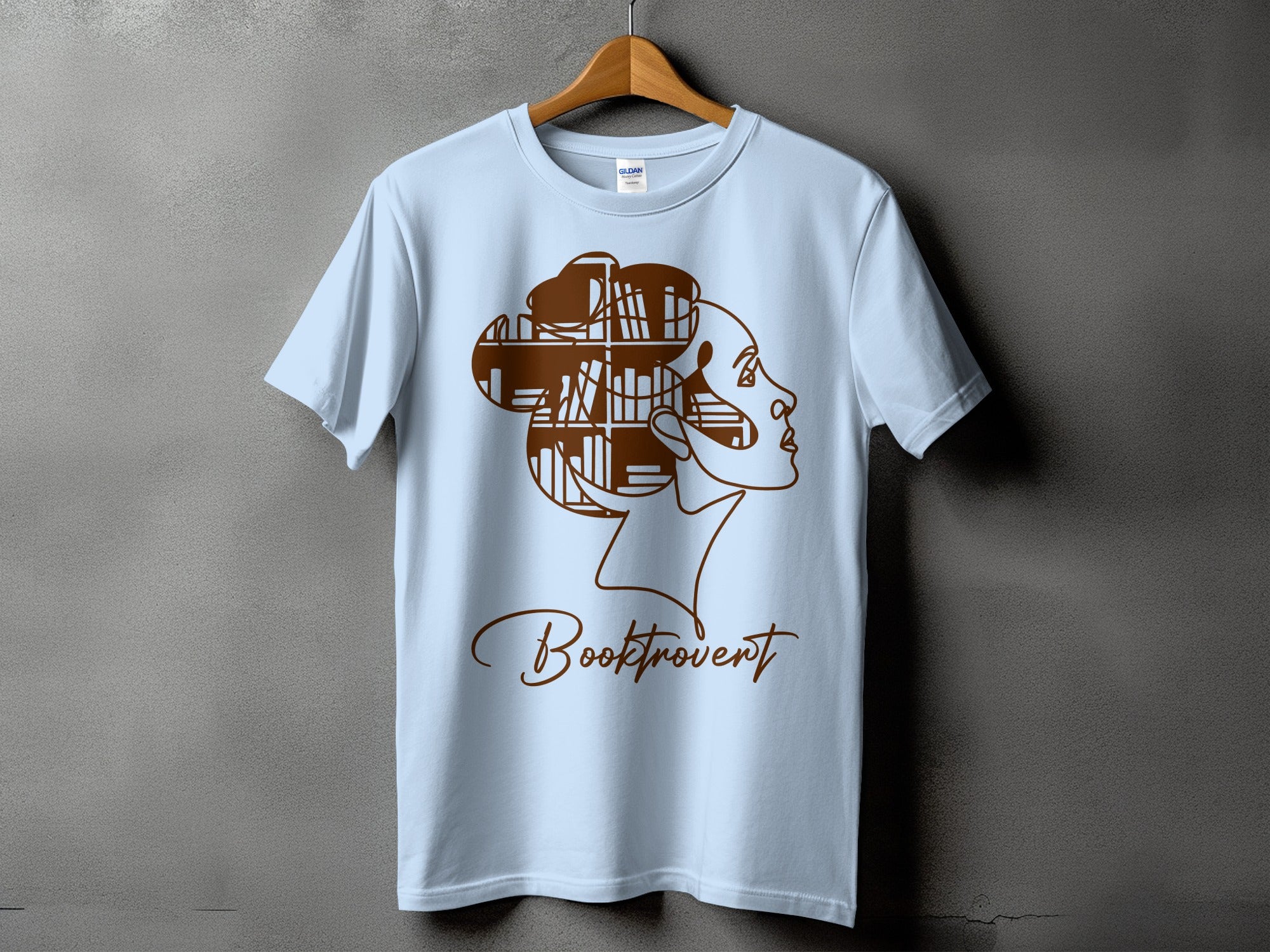 Light blue t-shirt with brown outline of a woman with bookshelves in her hair, text "Booktrovert".