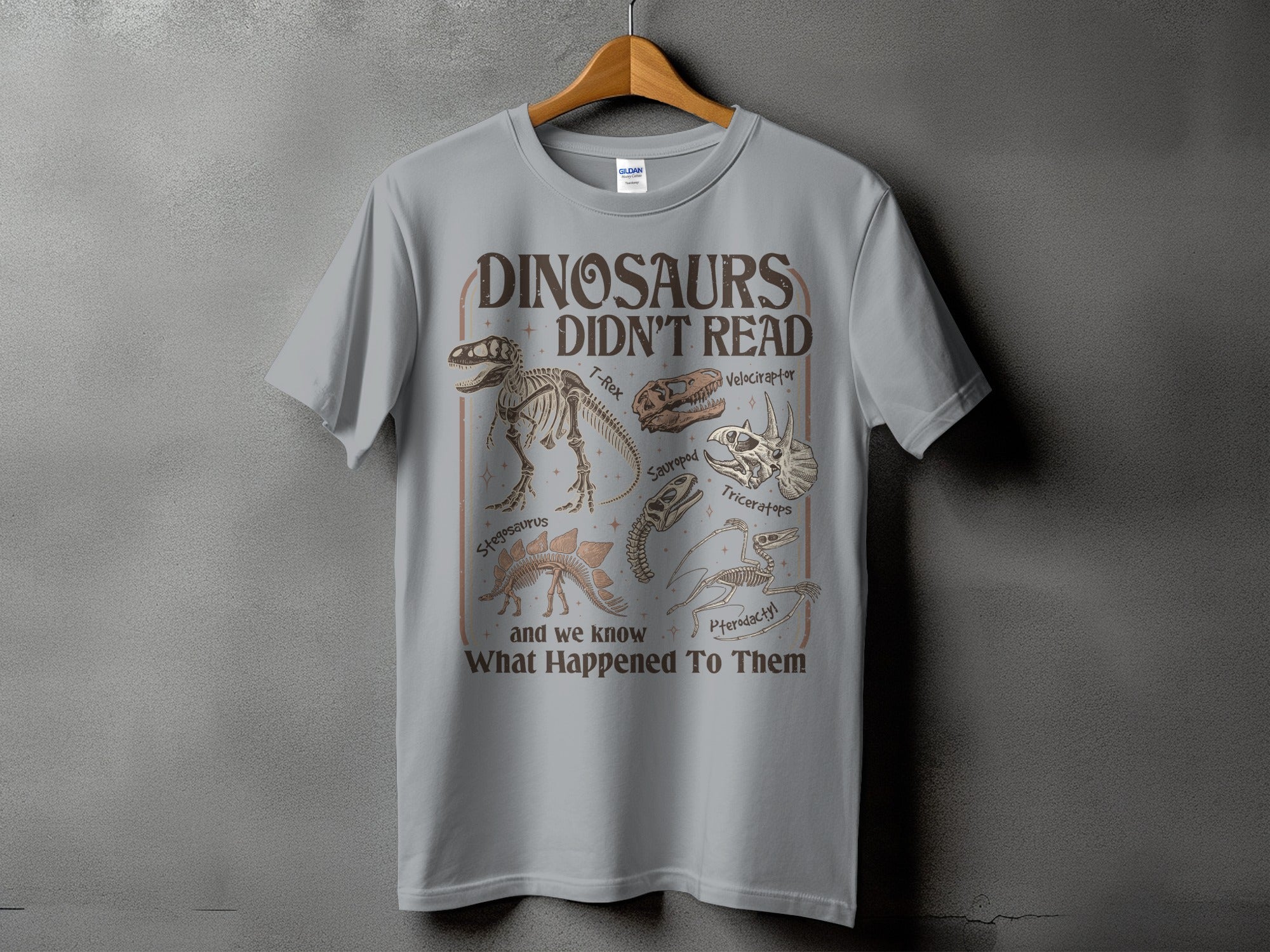 Gray t-shirt with dinosaur skeletons and text "Dinosaurs Didn't Read".