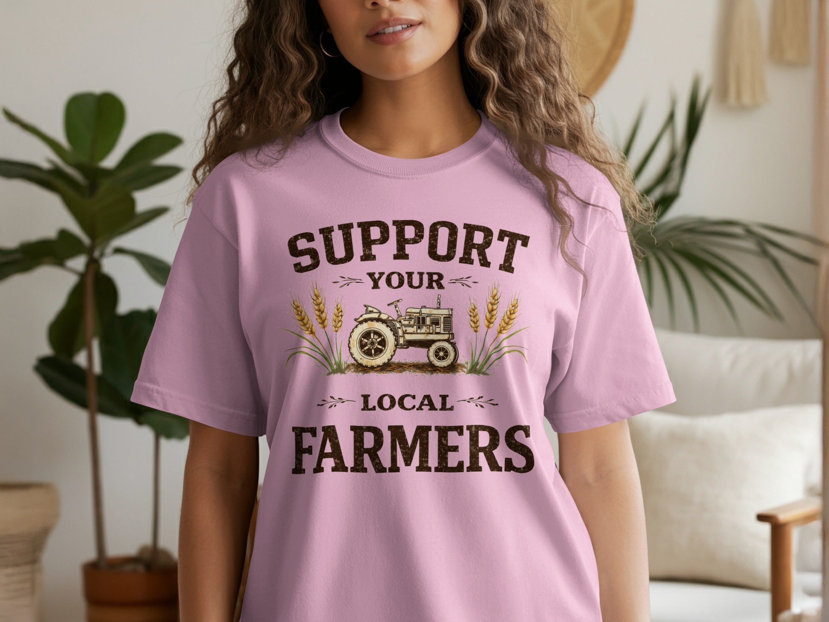 Support your local farmers text with tractor and wheat graphic on pink t-shirt.