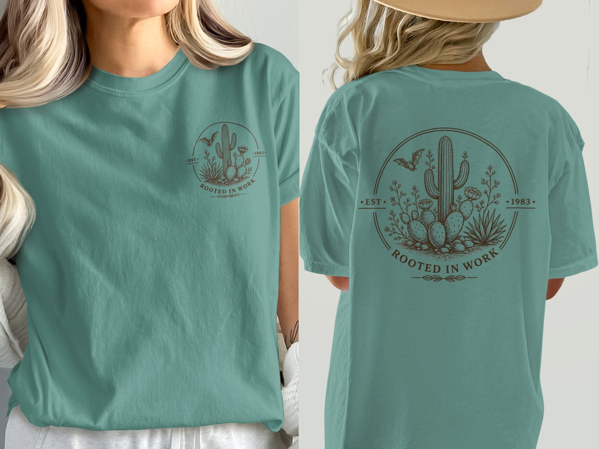 Teal t-shirt with circular desert graphic featuring cacti, bats, and text "Rooted in Work".