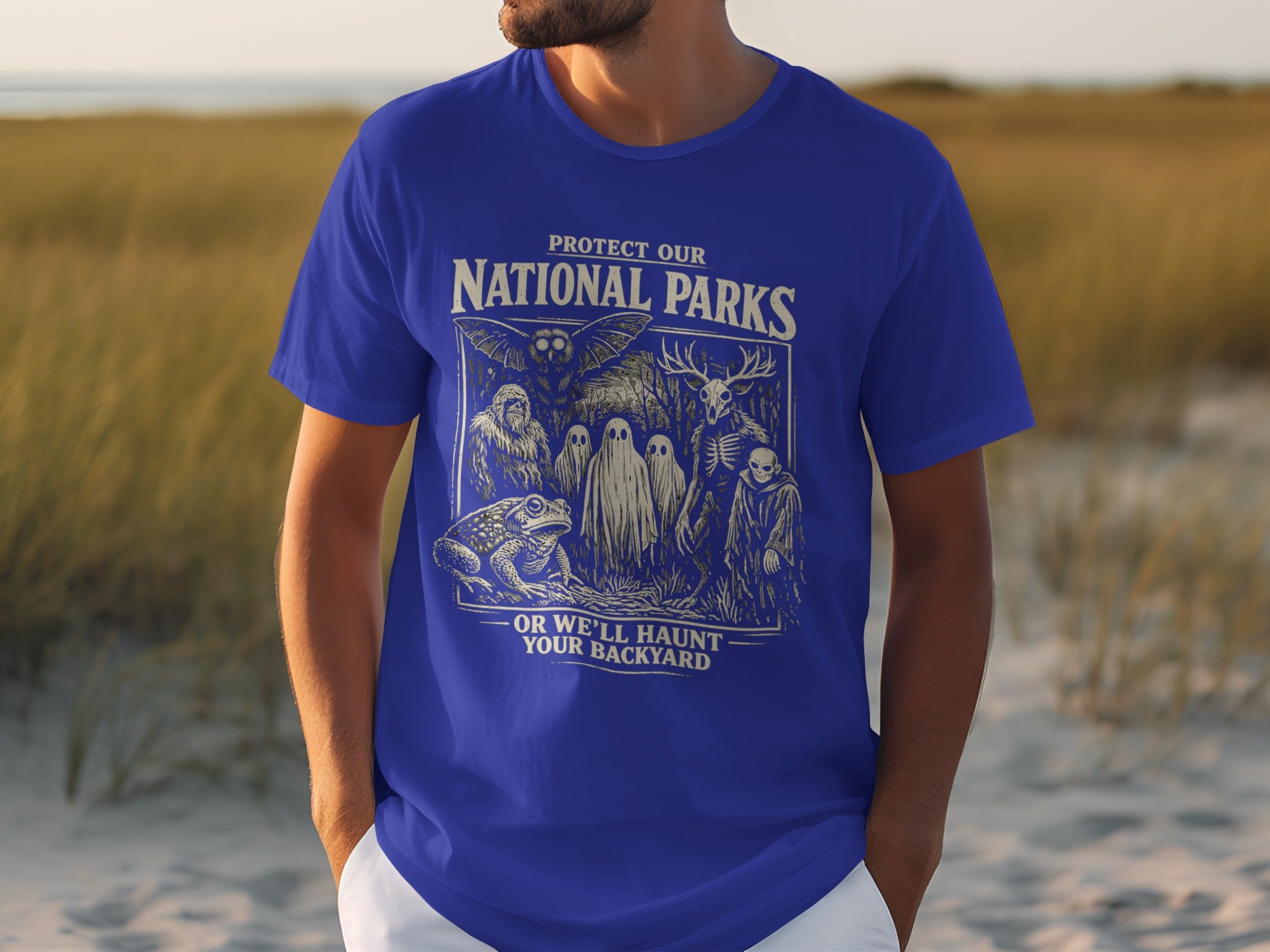 "Protect Our National Parks. Or We'll Haunt Your Backyard" text on a blue t-shirt with vintage-style graphics.