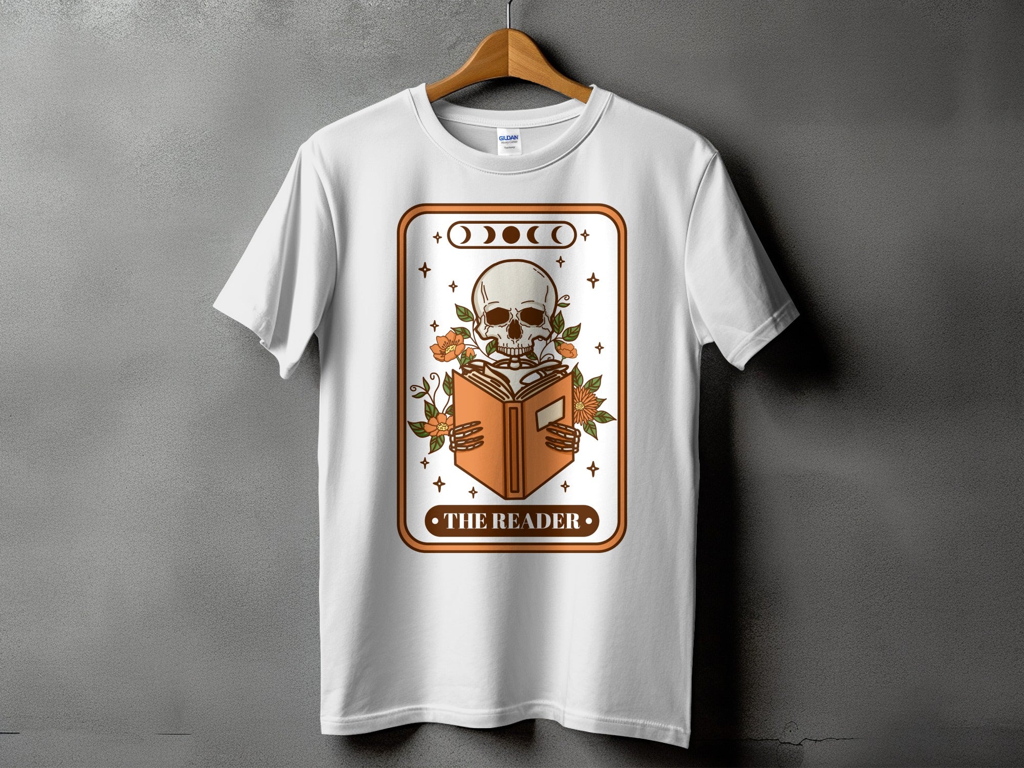 White t-shirt with a skeleton reading a book graphic and the text "THE READER".