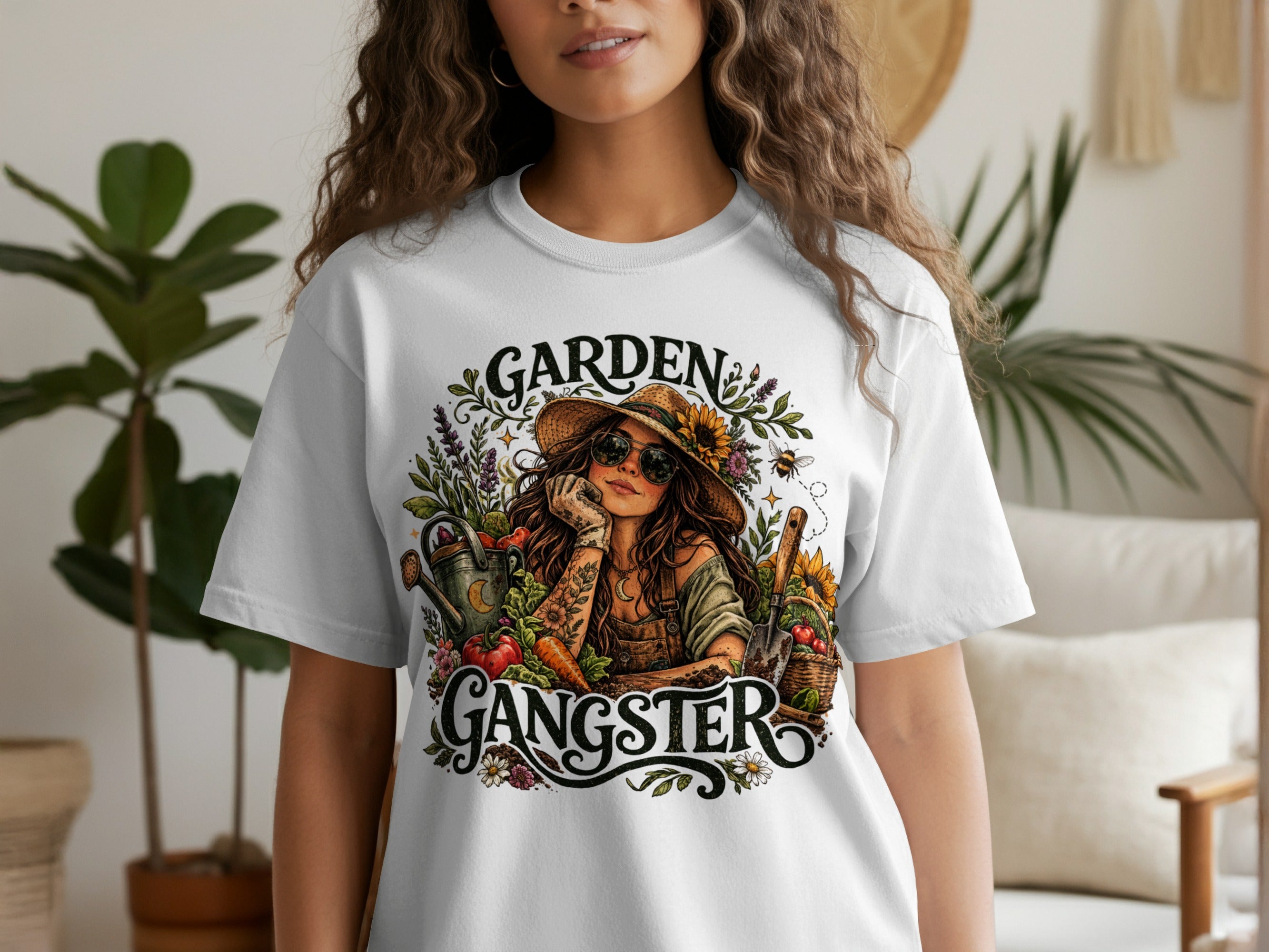 White t-shirt featuring graphic text "GARDEN GANGSTER" with a woman and garden elements.