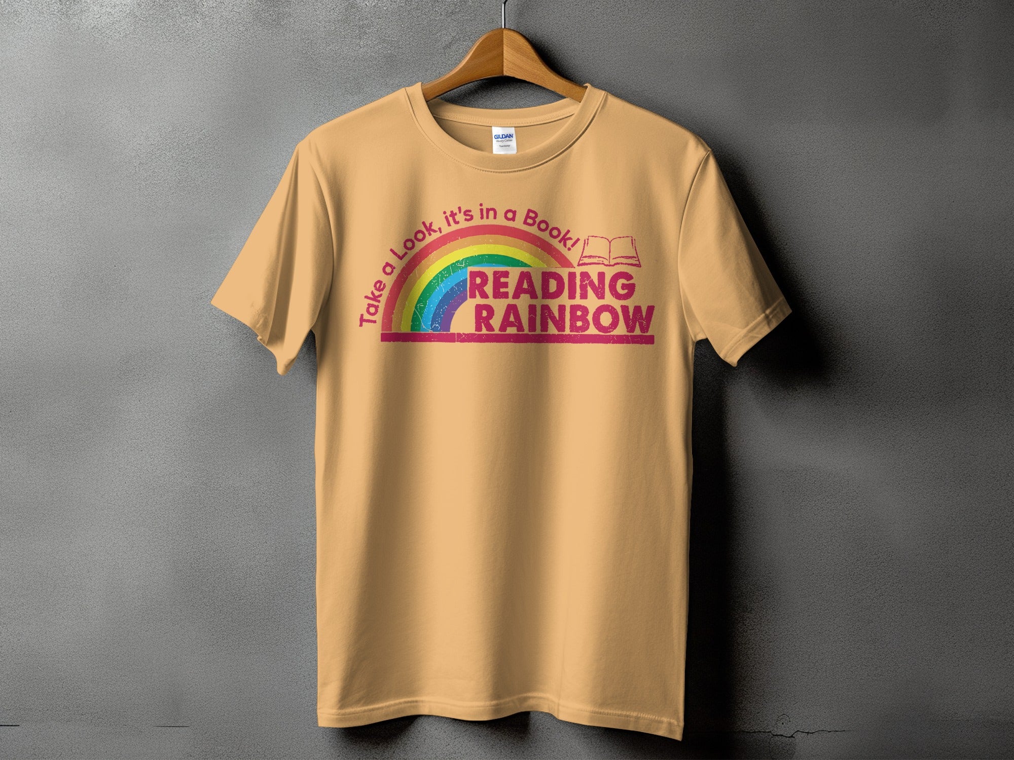 Peach t-shirt with rainbow graphic and text "Take a Look, it's in a Book! READING RAINBOW."