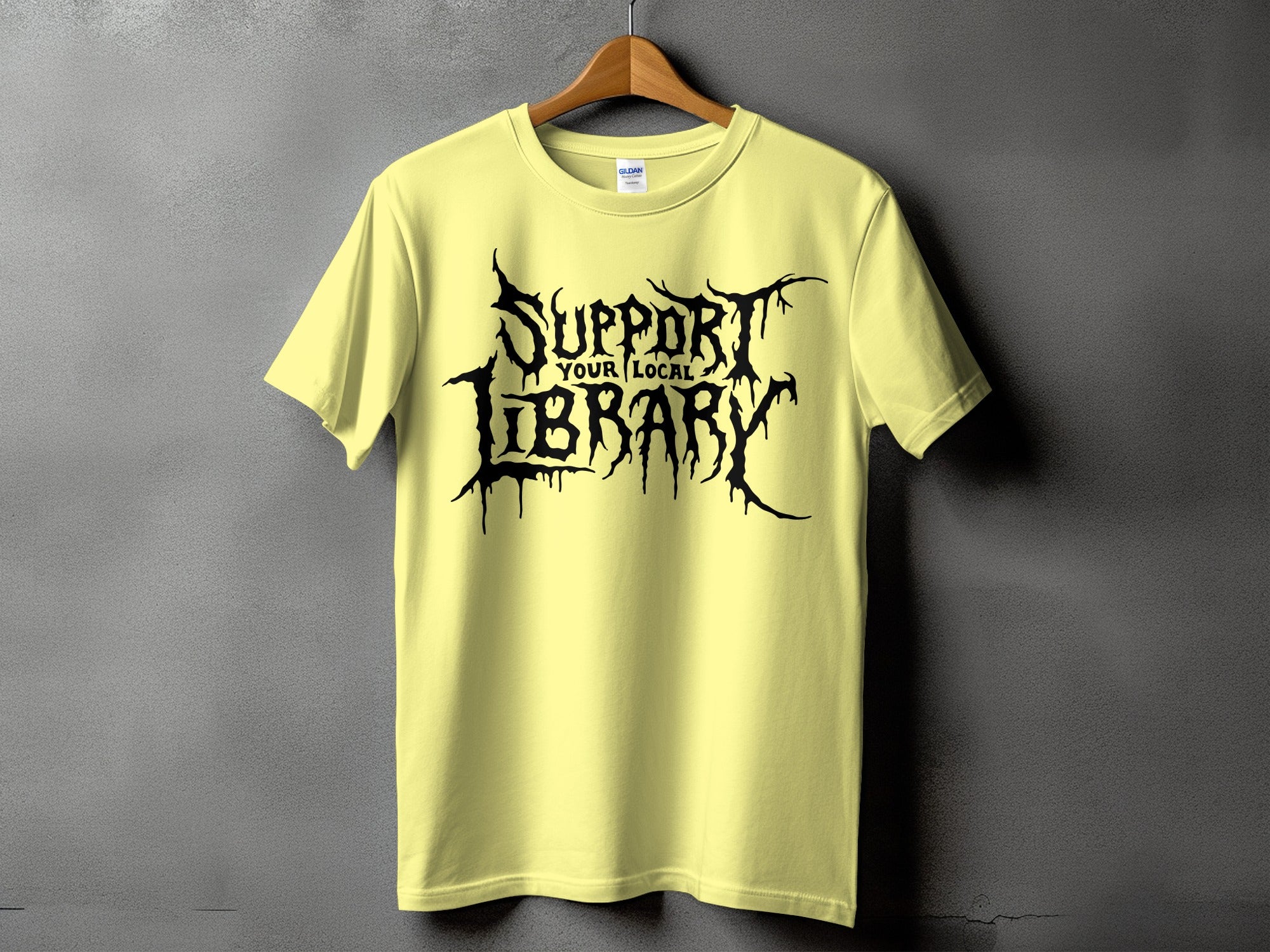 Light yellow t-shirt with "Support Your Local Library" in black gothic font.