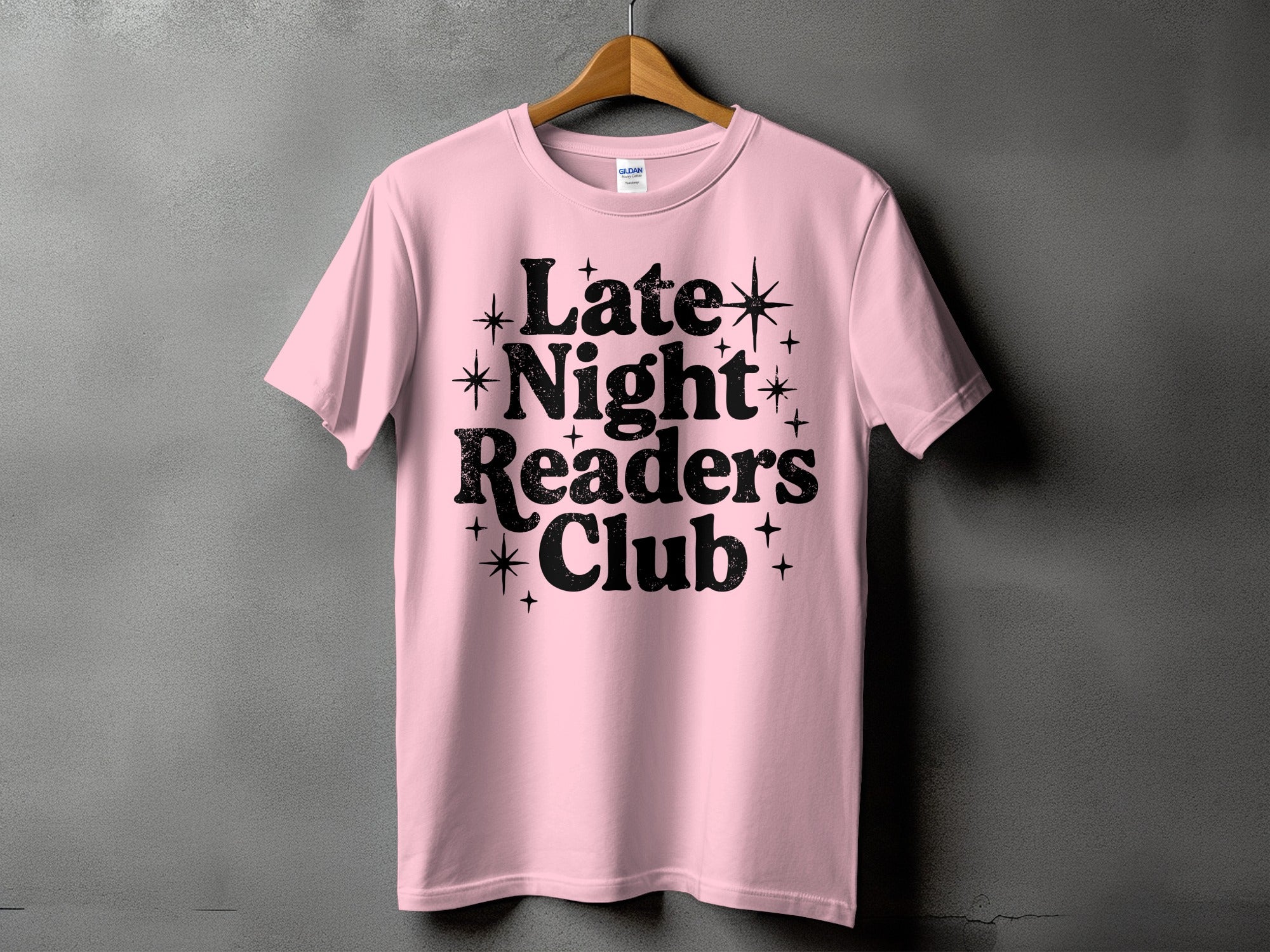 Pink t-shirt with black text "Late Night Readers Club" and star accents.
