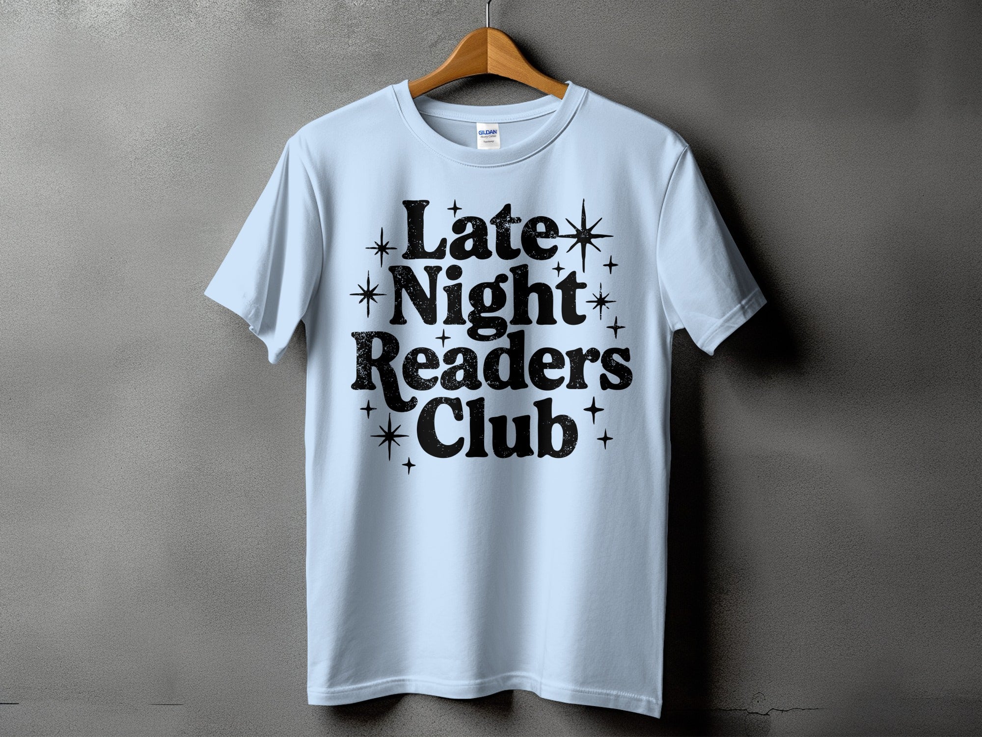 Light blue t-shirt with black text "Late Night Readers Club" and star accents.