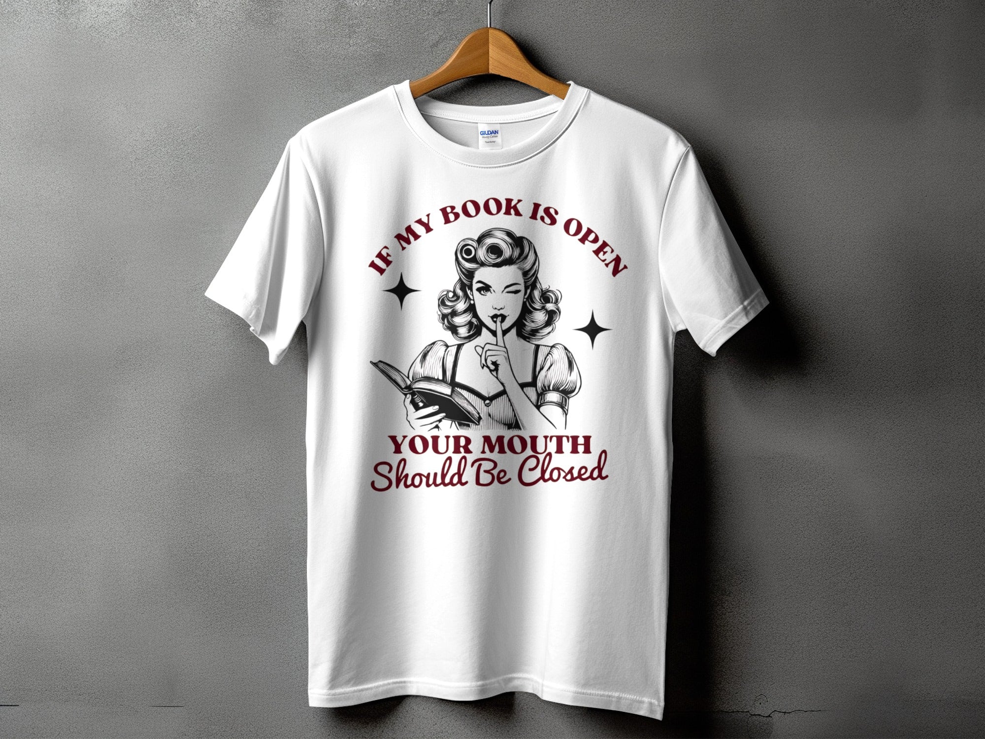 White t-shirt with retro pin-up art and text "If my book is open, your mouth should be closed."
