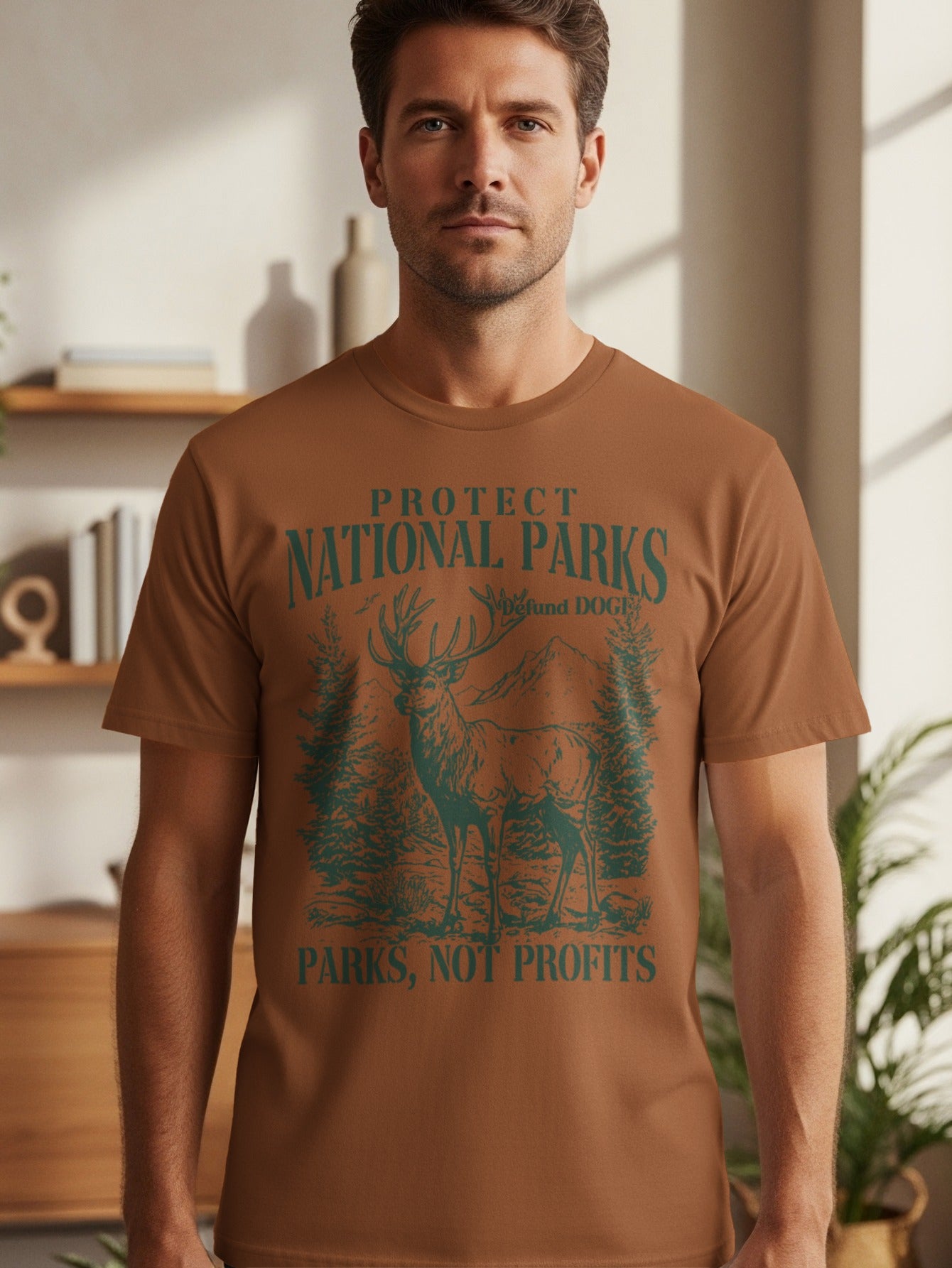 Brown t-shirt with green graphic of deer, trees, and mountains with text "Protect National Parks" and "Parks, Not Profits".