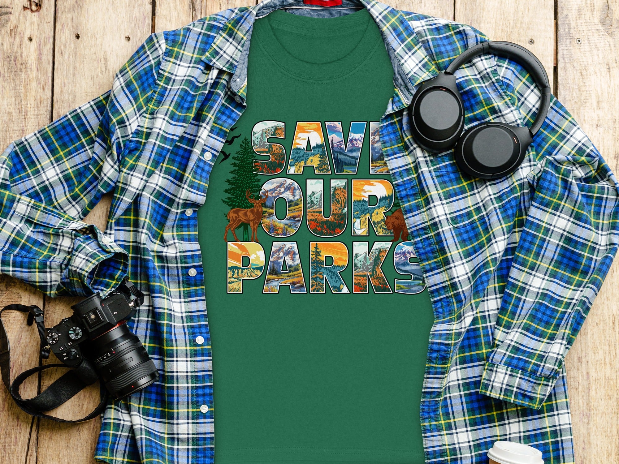 Green t-shirt with text "SAVE OUR PARKS" in scenic mountain, forest, and sunset graphics.