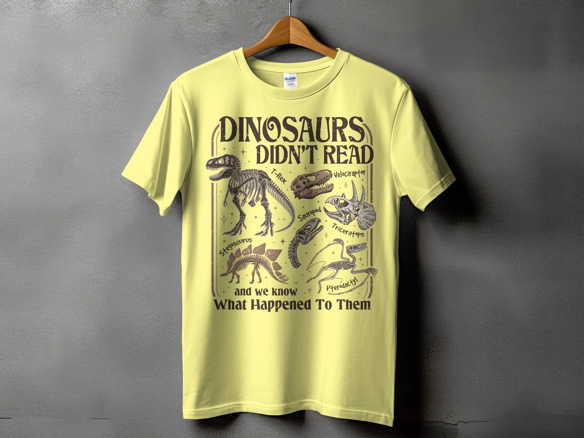 Yellow t-shirt with text Dinosaurs Didn't Read and illustrations of dinosaur skeletons.
