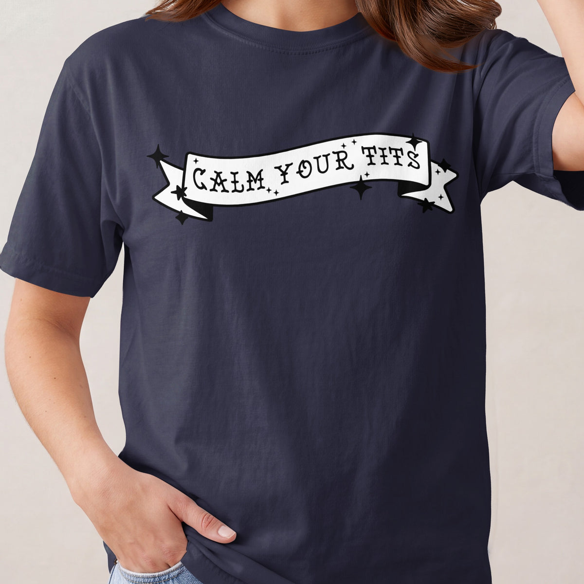 Navy t-shirt with white banner graphic that reads "CALM YOUR TITS".