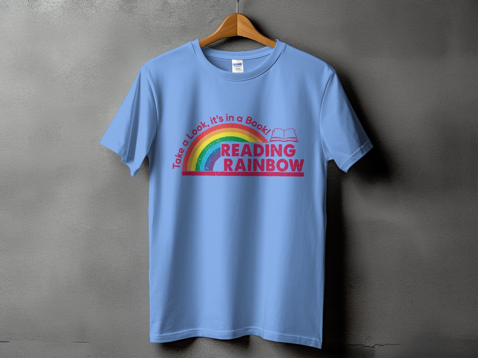 Blue t-shirt with rainbow graphic and text "Take a Look, it's in a Book! READING RAINBOW".
