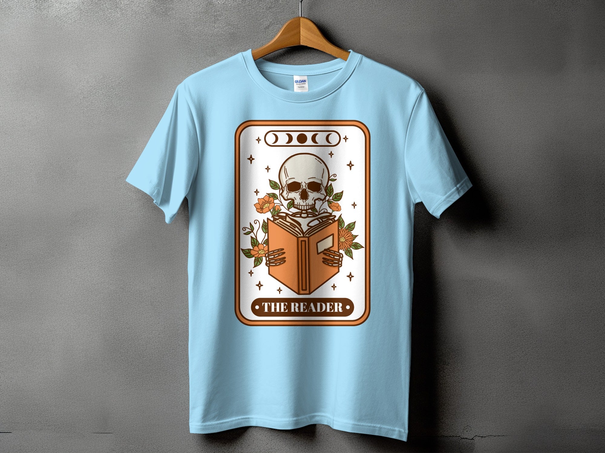 Light blue t-shirt with a graphic of a skeleton reading a book titled "The Reader".