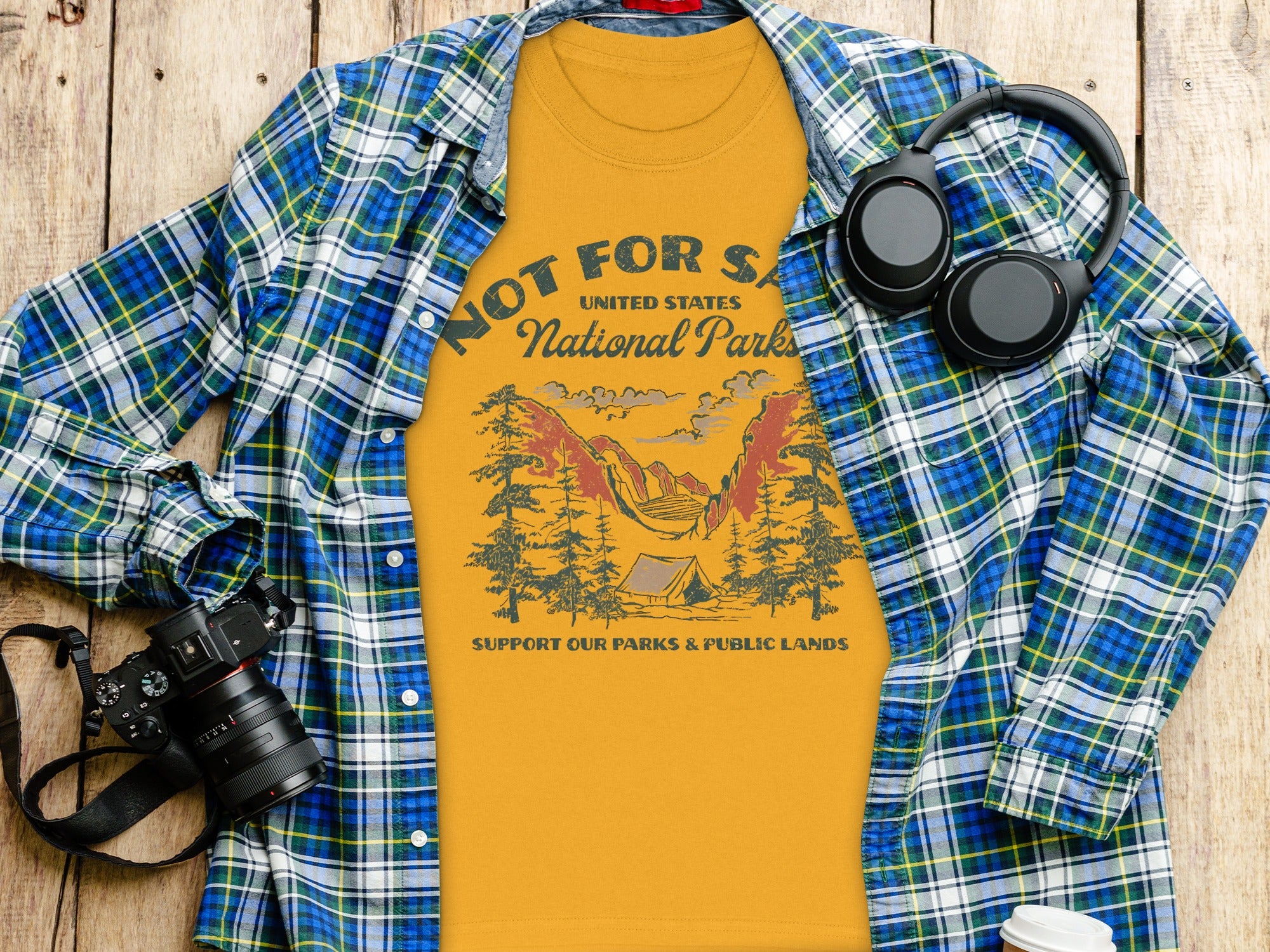 Yellow t-shirt with "National Parks" graphic, plaid shirt, headphones, and camera.