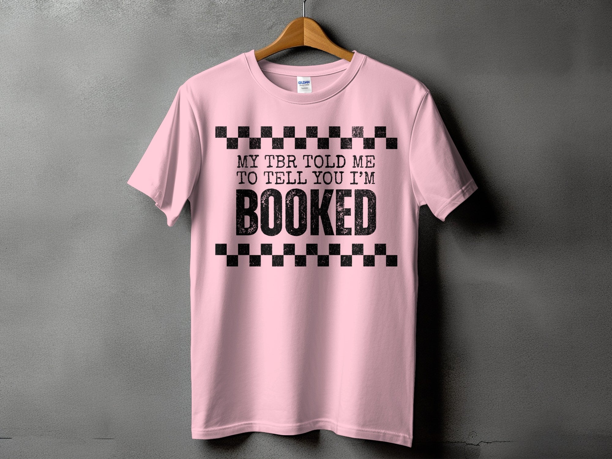 Pink t-shirt with black text "MY TBR TOLD ME TO TELL YOU I'M BOOKED".