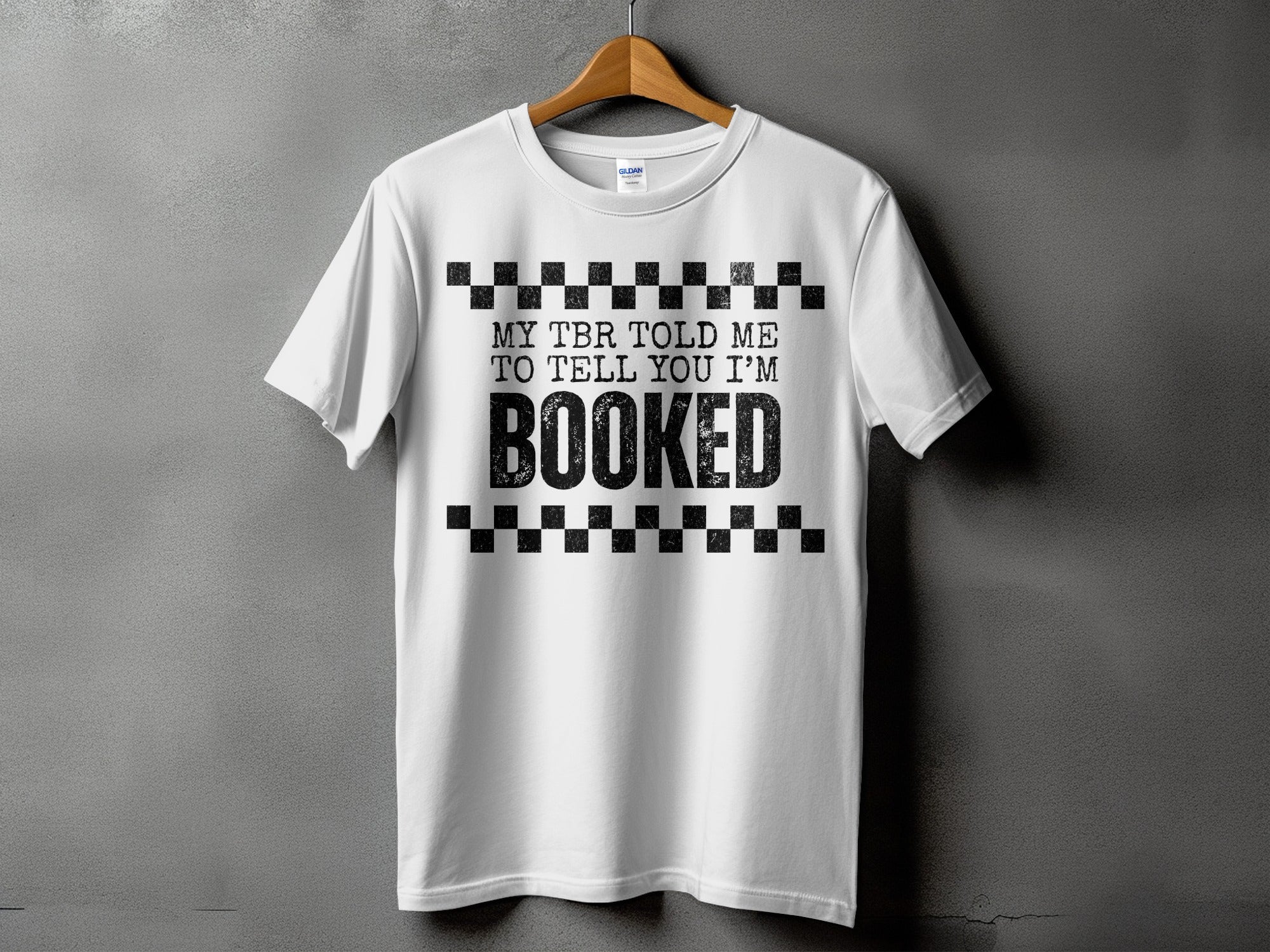 White t-shirt with black text "MY TBR TOLD ME TO TELL YOU I'M BOOKED"
