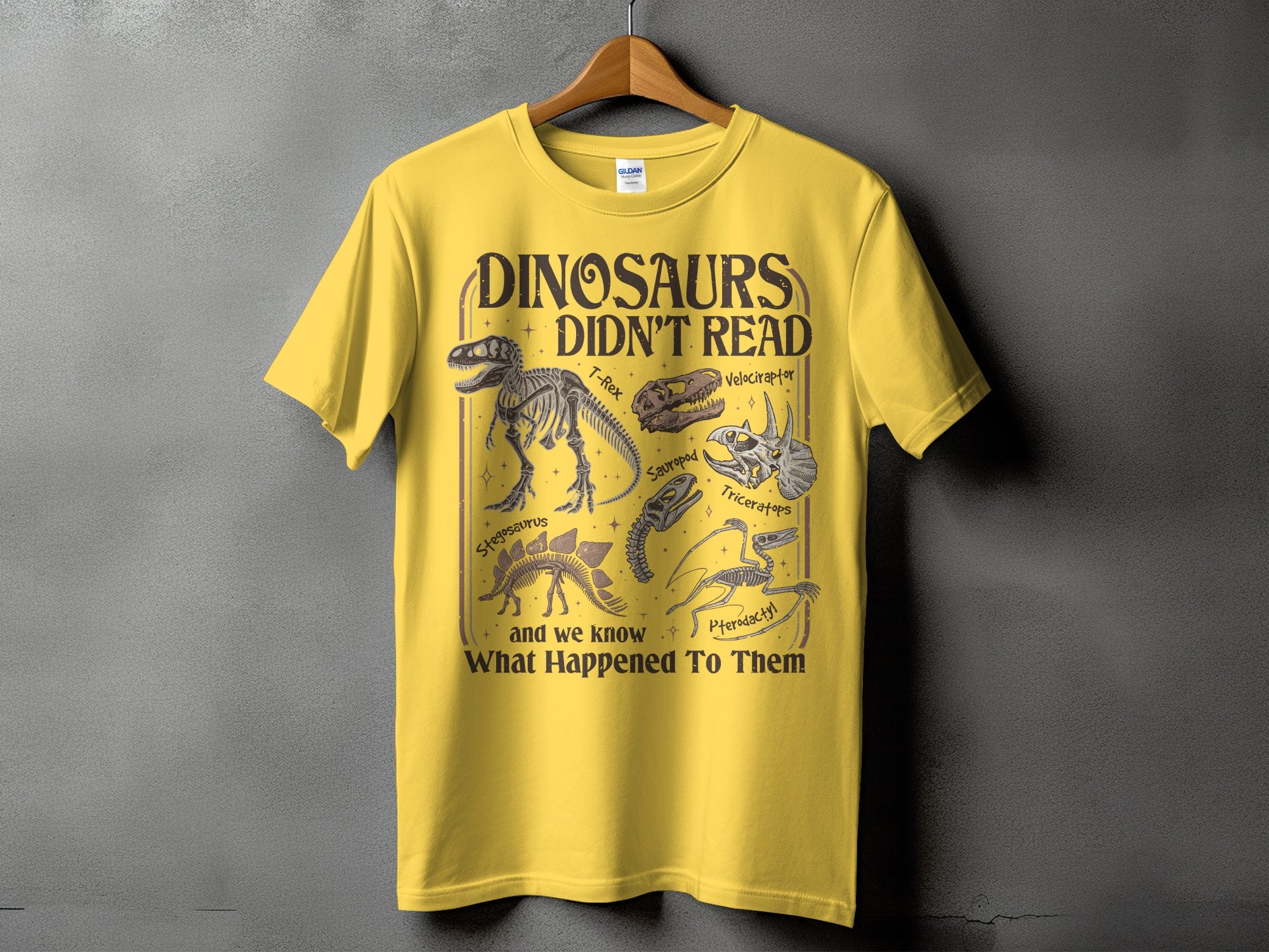 Yellow t-shirt with "Dinosaurs Didn't Read" and dinosaur skeletons.