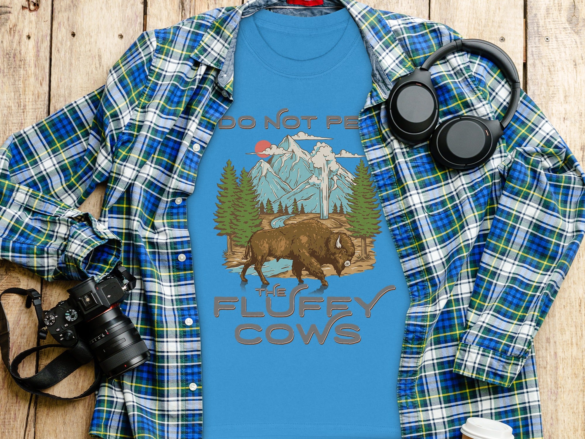 Blue t-shirt with text and graphics of a bison, mountains, and trees.