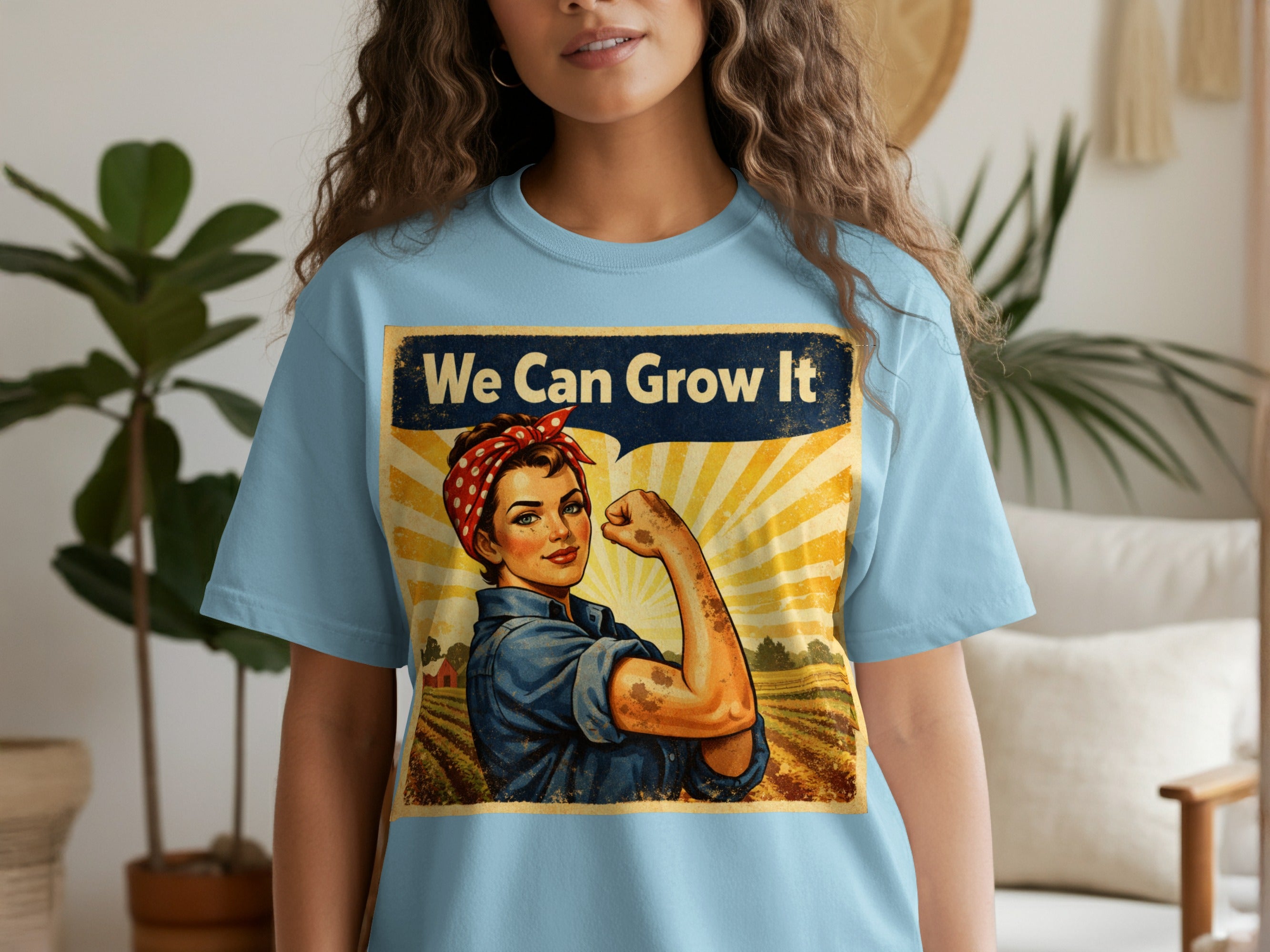 Light blue t-shirt featuring "We Can Grow It" text with a Rosie the Riveter-style agricultural worker.