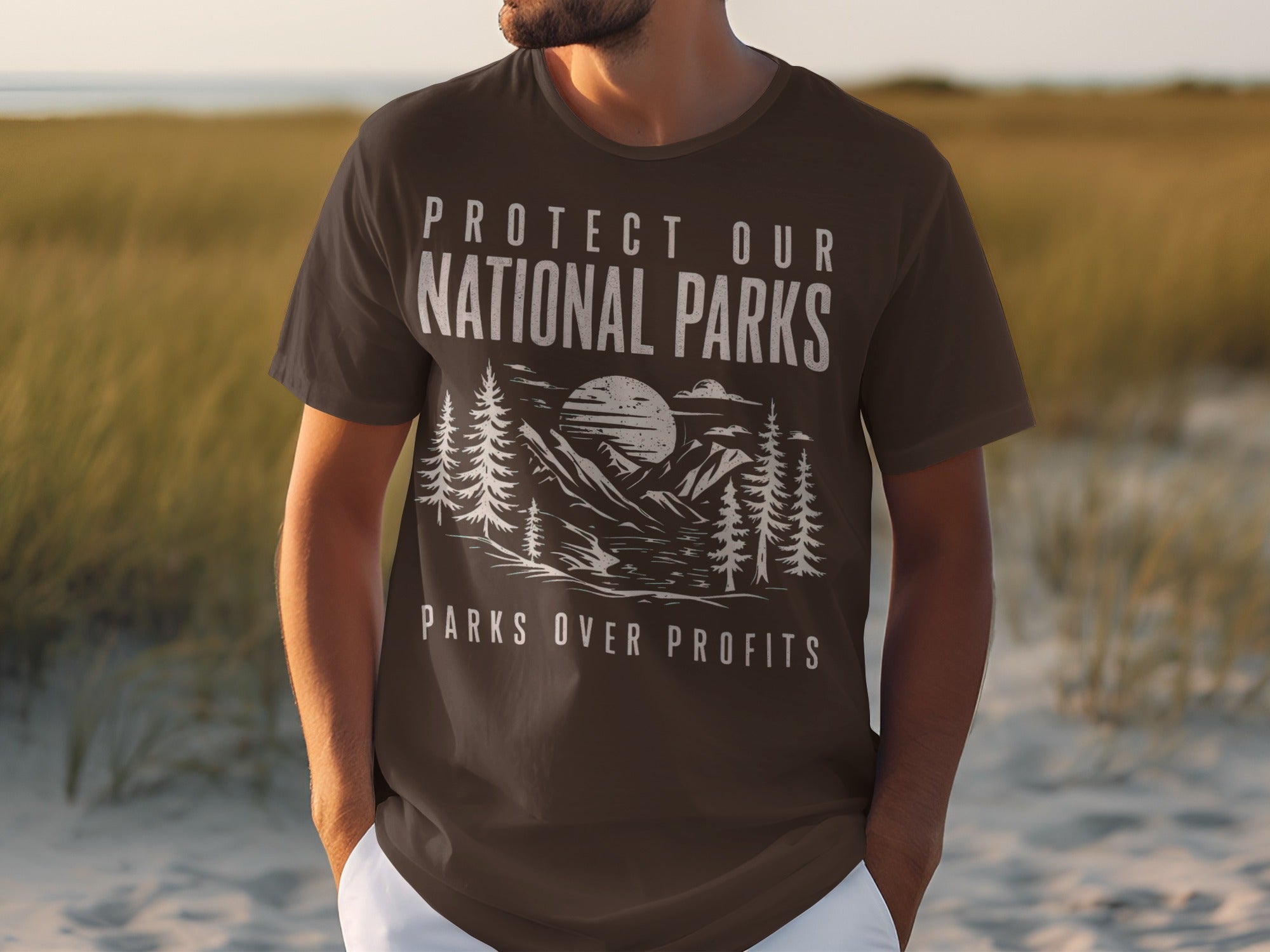Brown t-shirt with text "Protect Our National Parks" and "Parks Over Profits" displayed over a landscape.