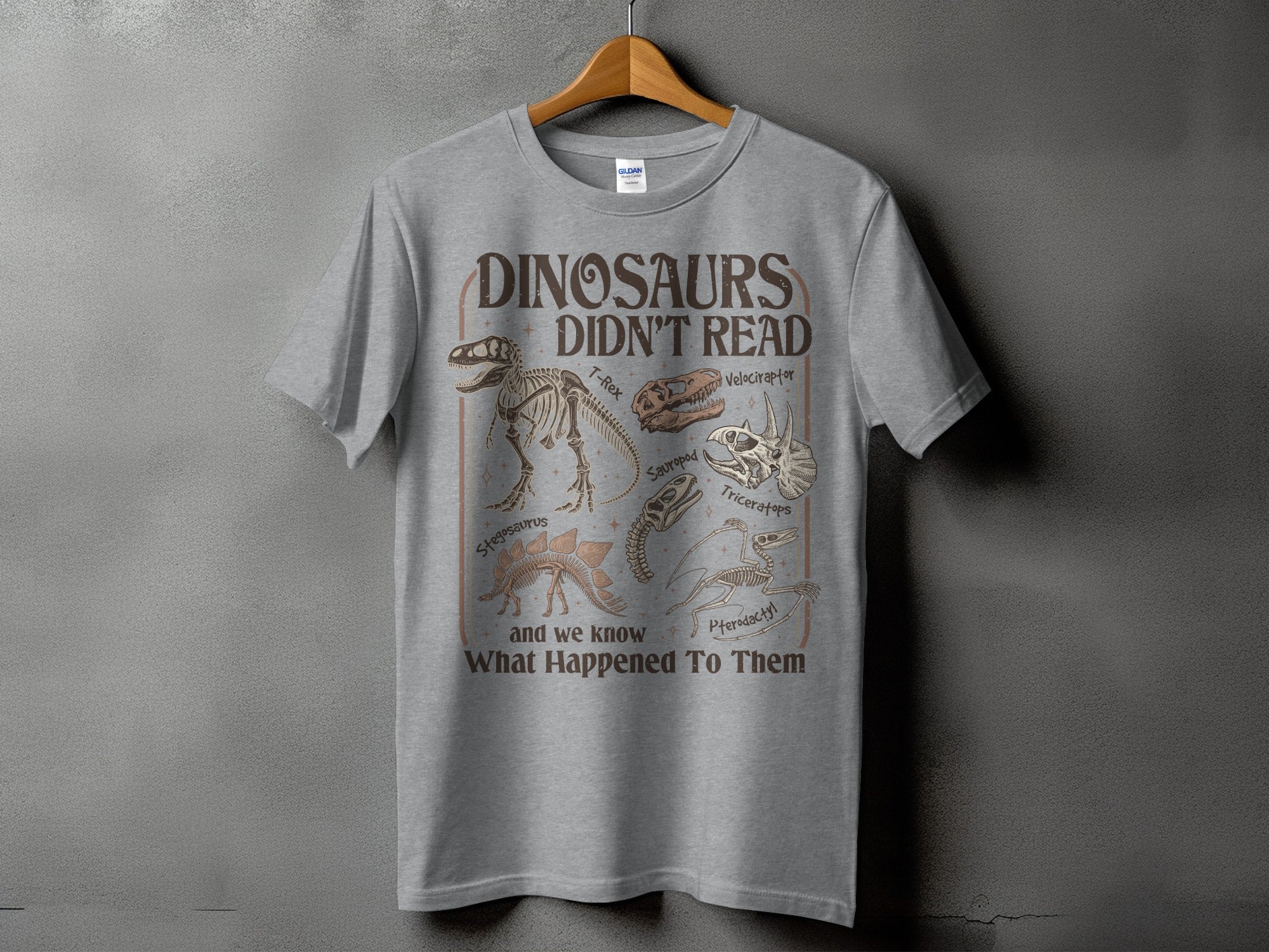 Grey t-shirt with "Dinosaurs Didn't Read" and dinosaur skeletons.