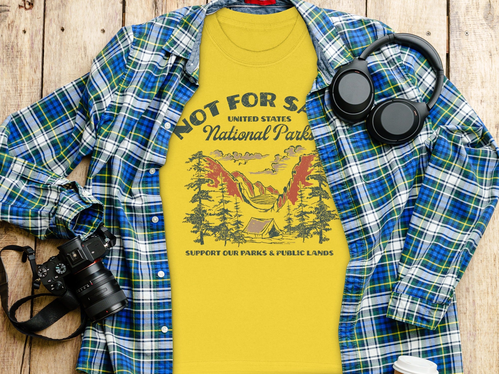 Yellow t-shirt with National Parks graphic, plaid shirt, headphones, and camera.