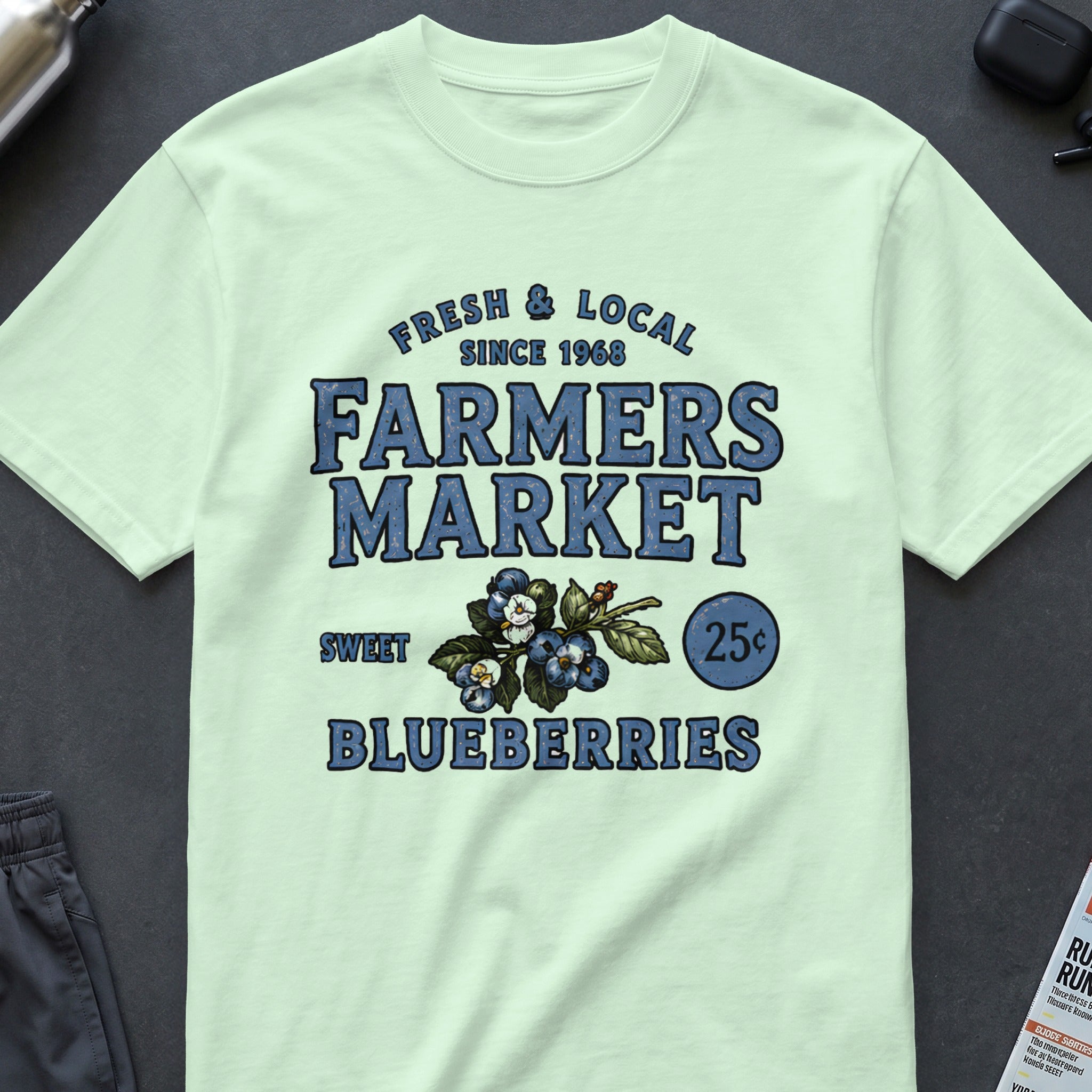 Pale green t-shirt with "Farmers Market Fresh & Local Since 1968 Blueberries" graphic.