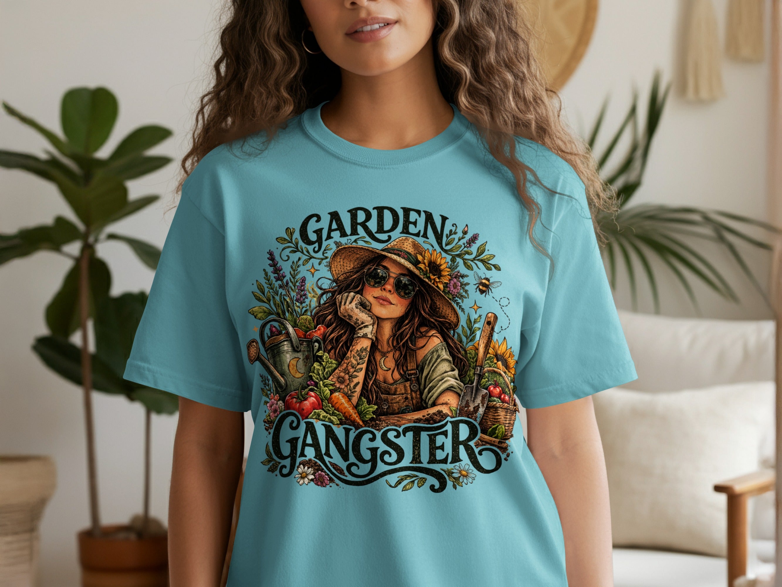 Graphic art on a light blue t-shirt depicts a woman gardening with text "GARDEN GANGSTER".