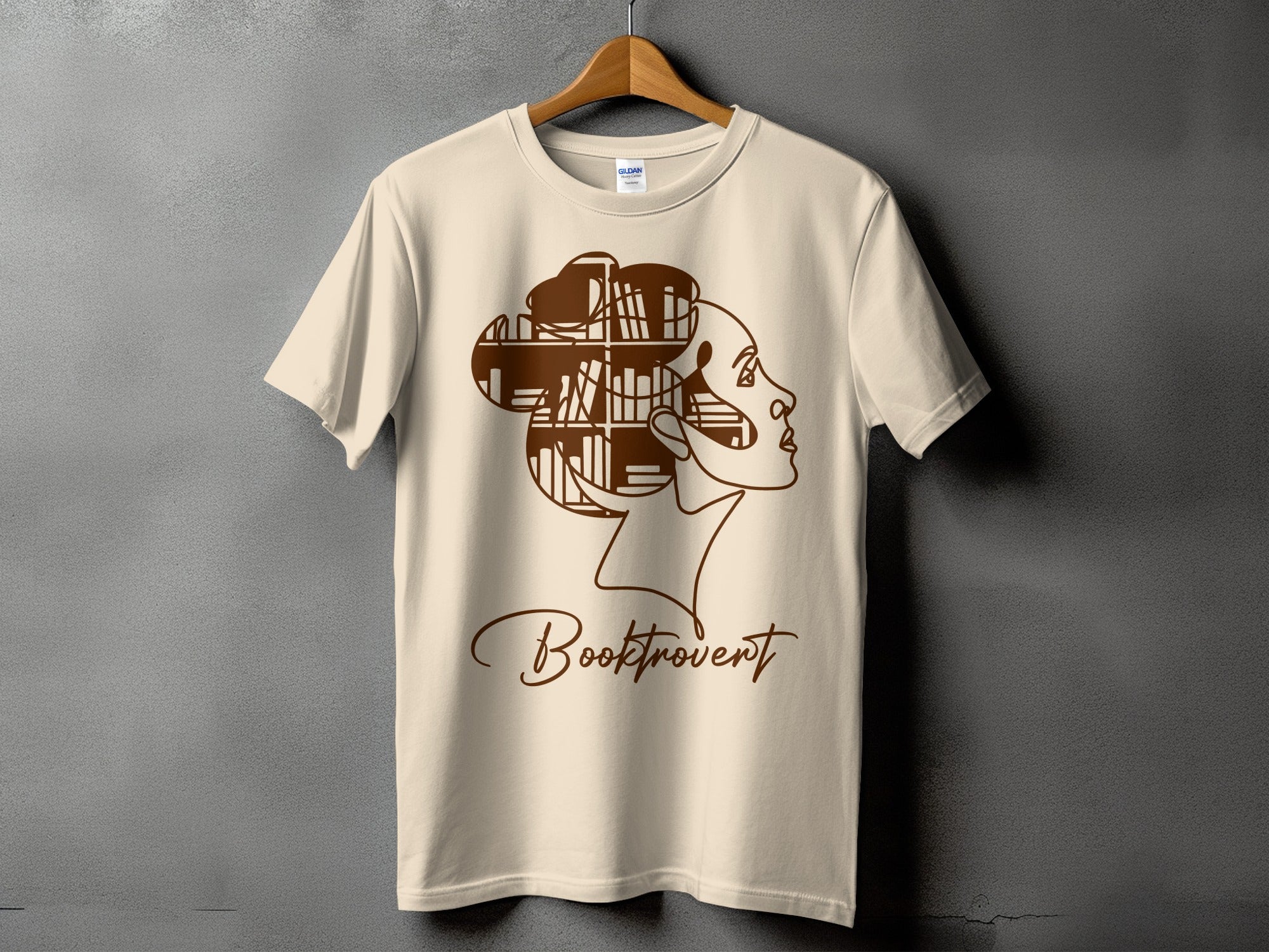 Light beige t-shirt with "Booktrovert" text and a profile of a woman whose hair is made of bookshelves.