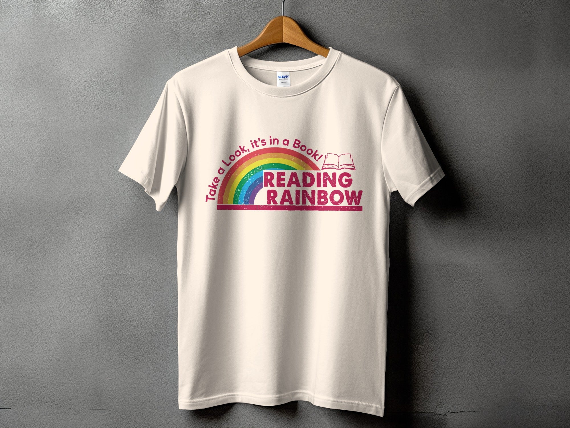 Cream t-shirt with rainbow graphic and text: "Take a Look, it's in a Book! READING RAINBOW"