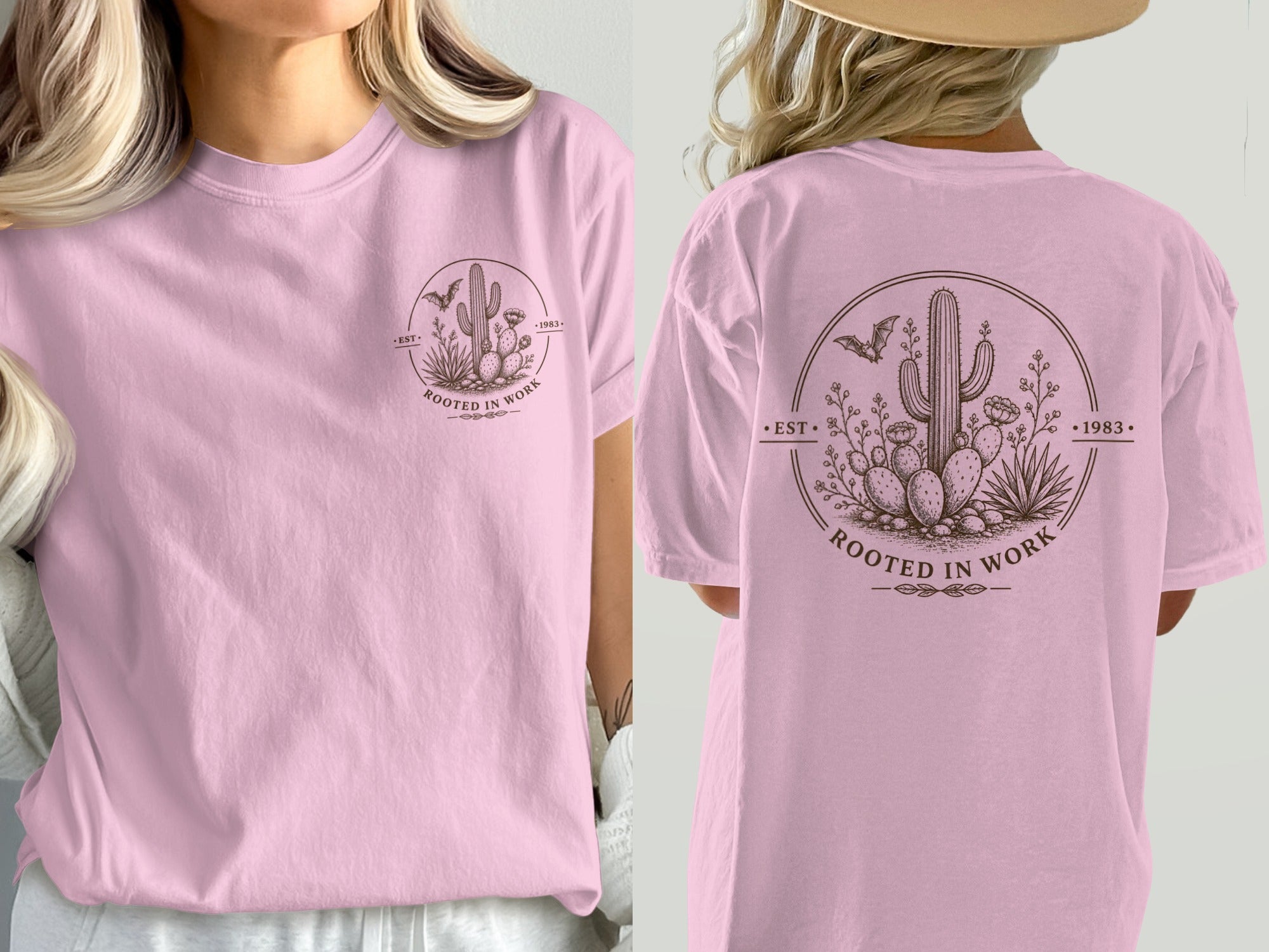 Pink t-shirt with a circular desert graphic featuring a saguaro cactus, bats, and "ROOTED IN WORK".