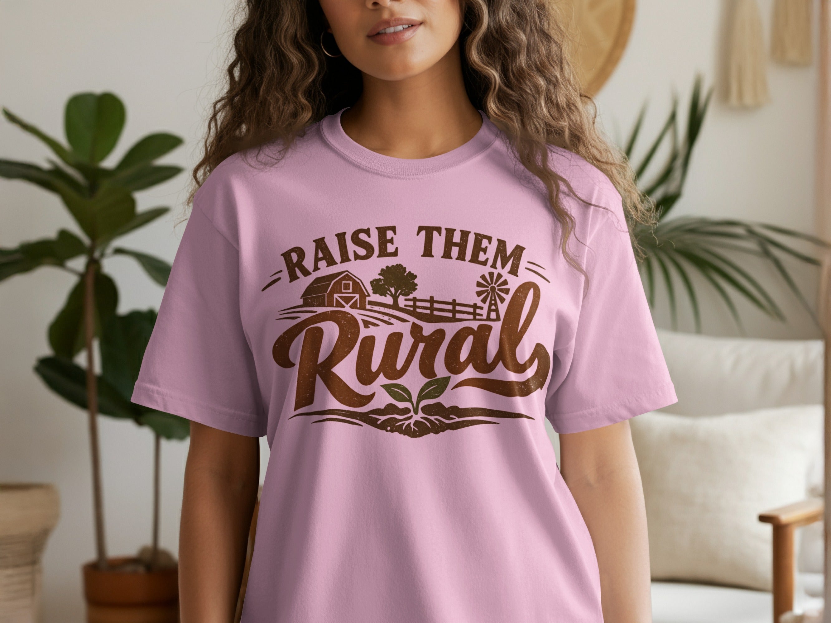 Pink t-shirt with "Raise Them Rural" text and farm graphic.