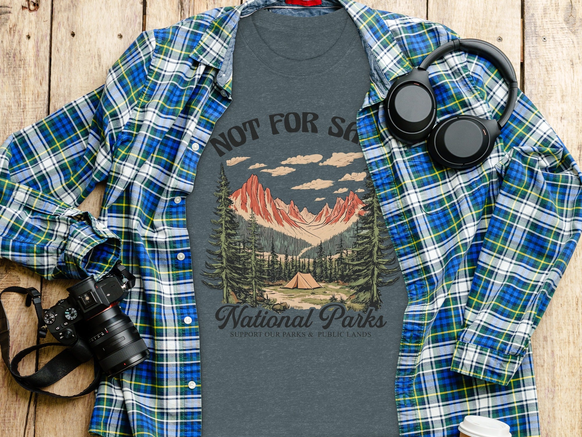 Dark grey t-shirt with national park graphic over blue plaid shirt.