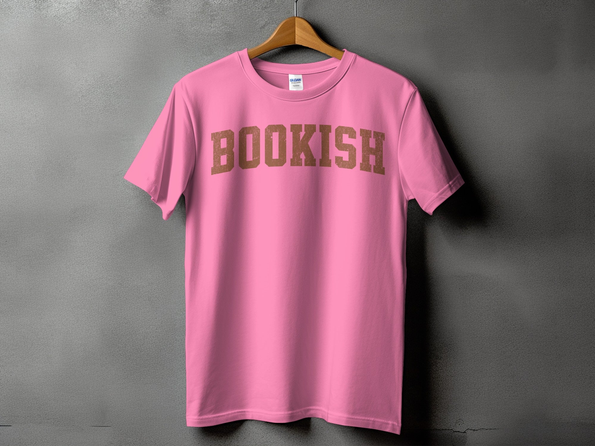 Pink t-shirt with "BOOKISH" in distressed brown block letters on a gray background.