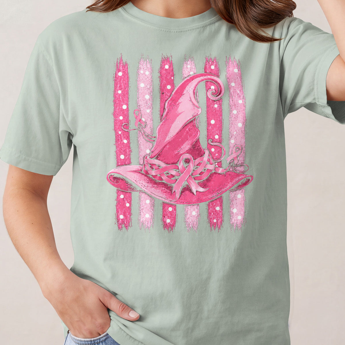 Pink witch hat with breast cancer ribbons on striped background.