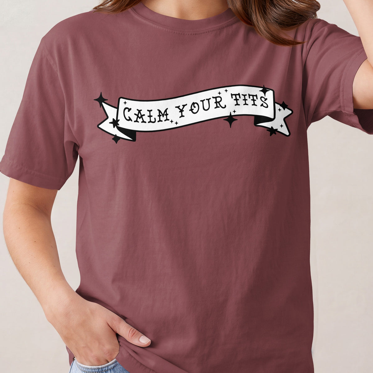T-shirt with "CALM YOUR TITS" text on a banner graphic.