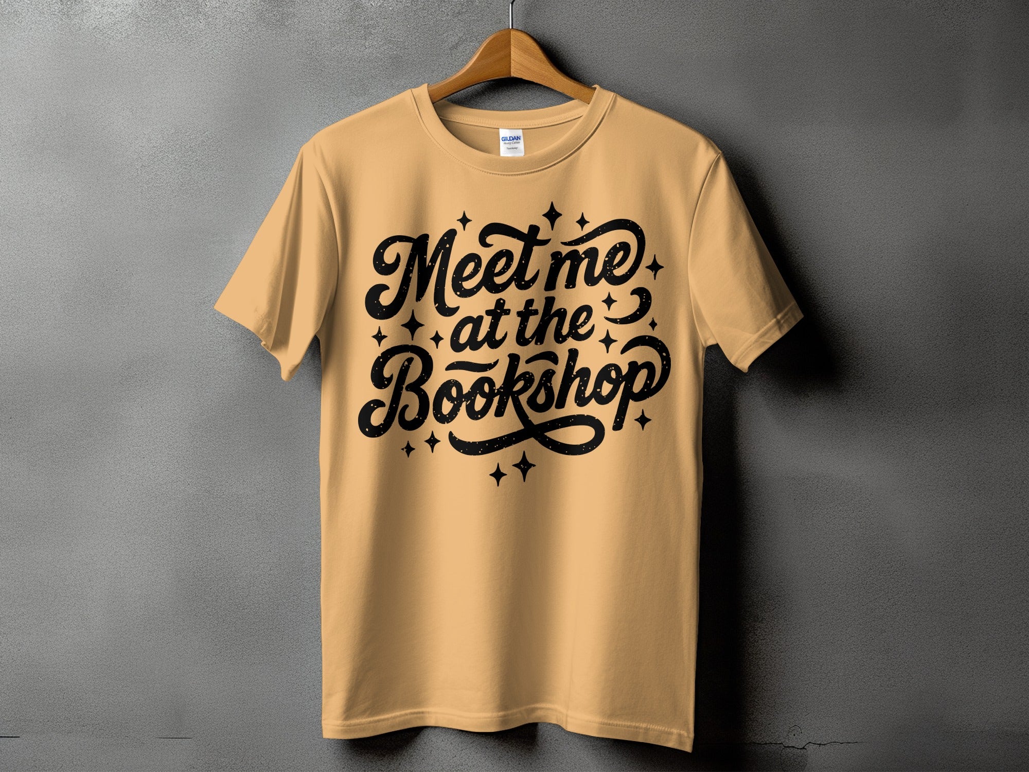 Tan t-shirt with "Meet me at the Bookshop" text in black script.