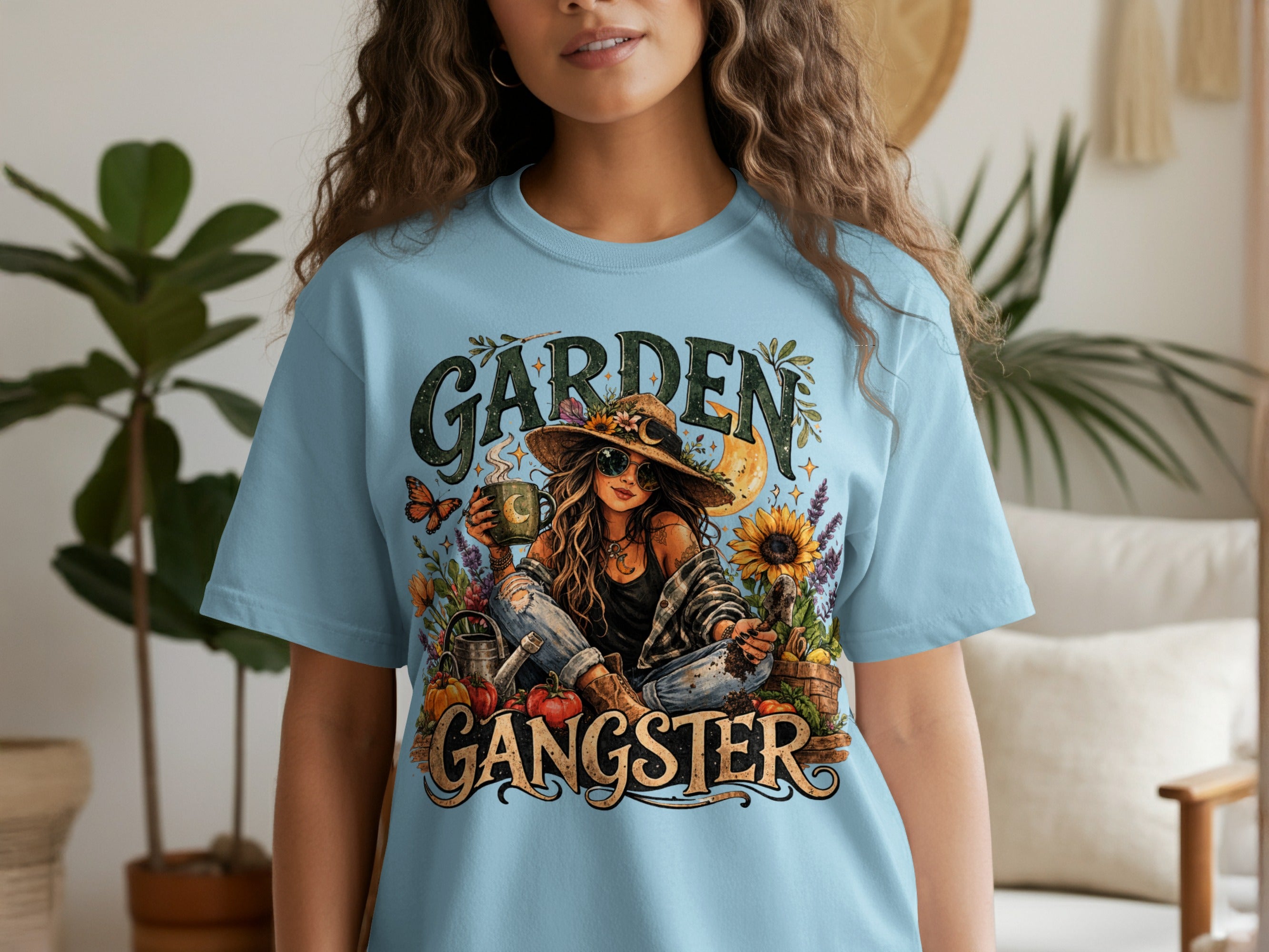 Light blue t-shirt graphic with "GARDEN GANGSTER" text, woman, sunflowers, butterflies and produce.