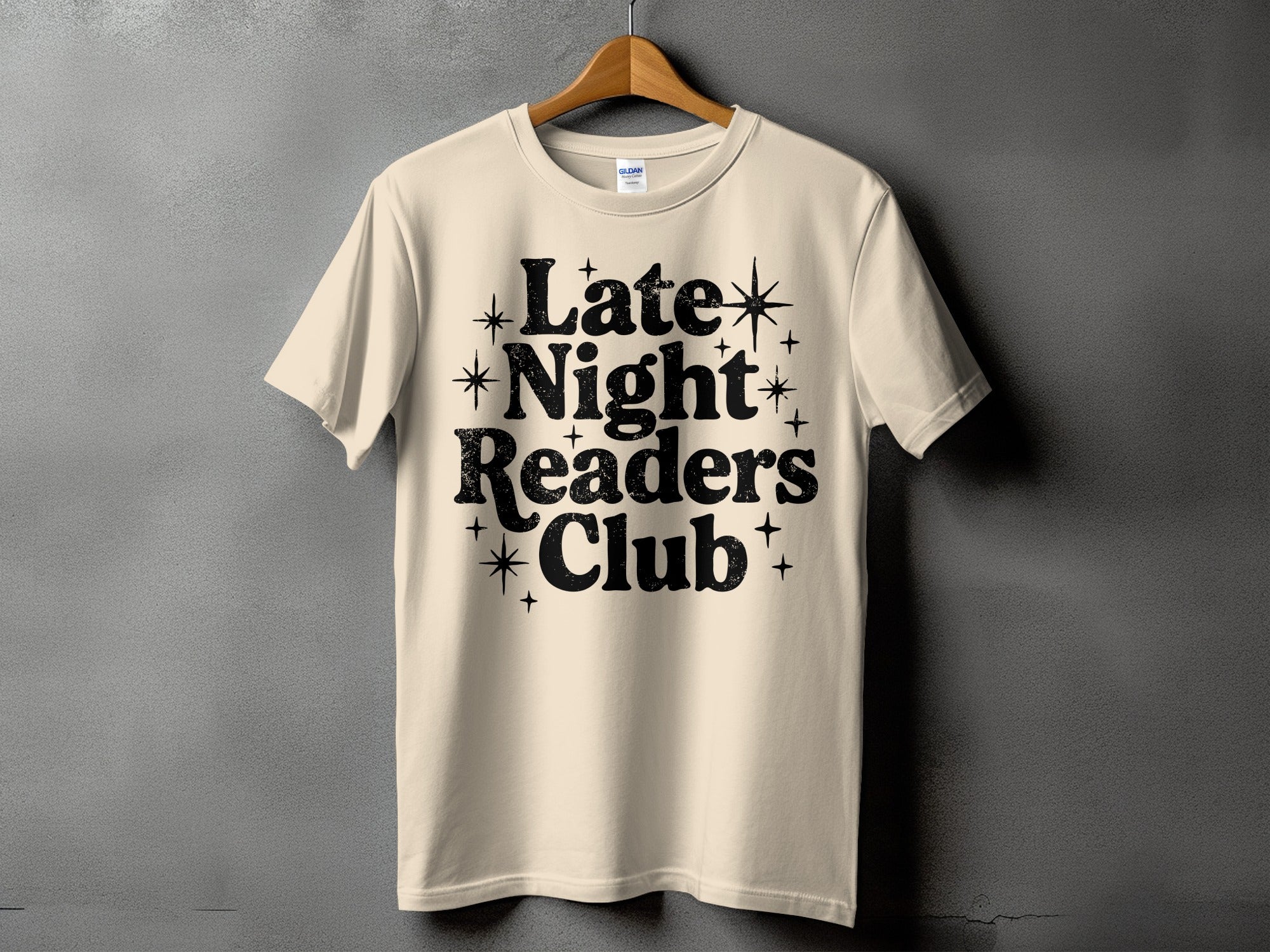 Cream t-shirt with black text "Late Night Readers Club" and decorative stars.