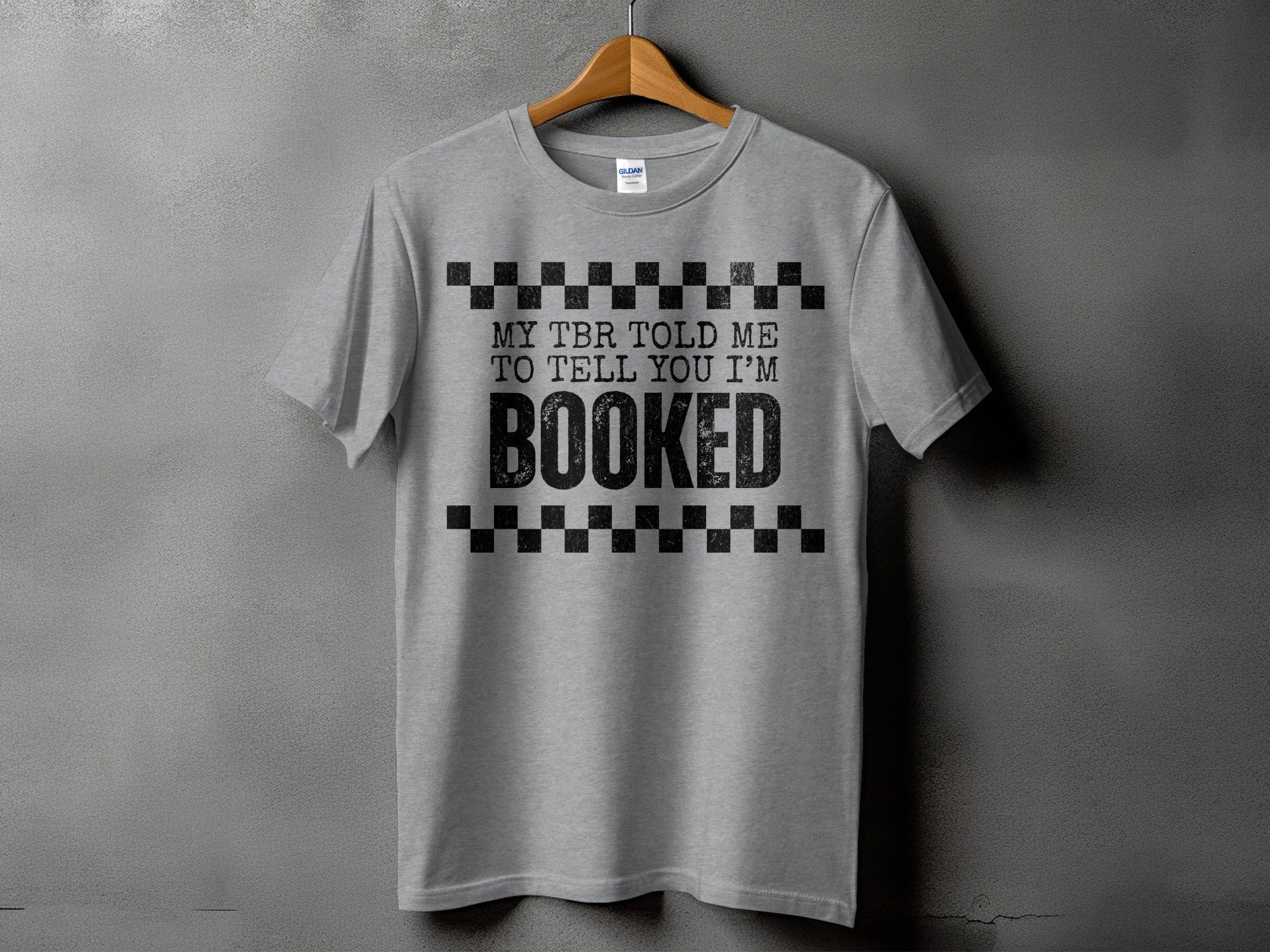 Grey t-shirt with black text reading "MY TBR TOLD ME TO TELL YOU I'M BOOKED".