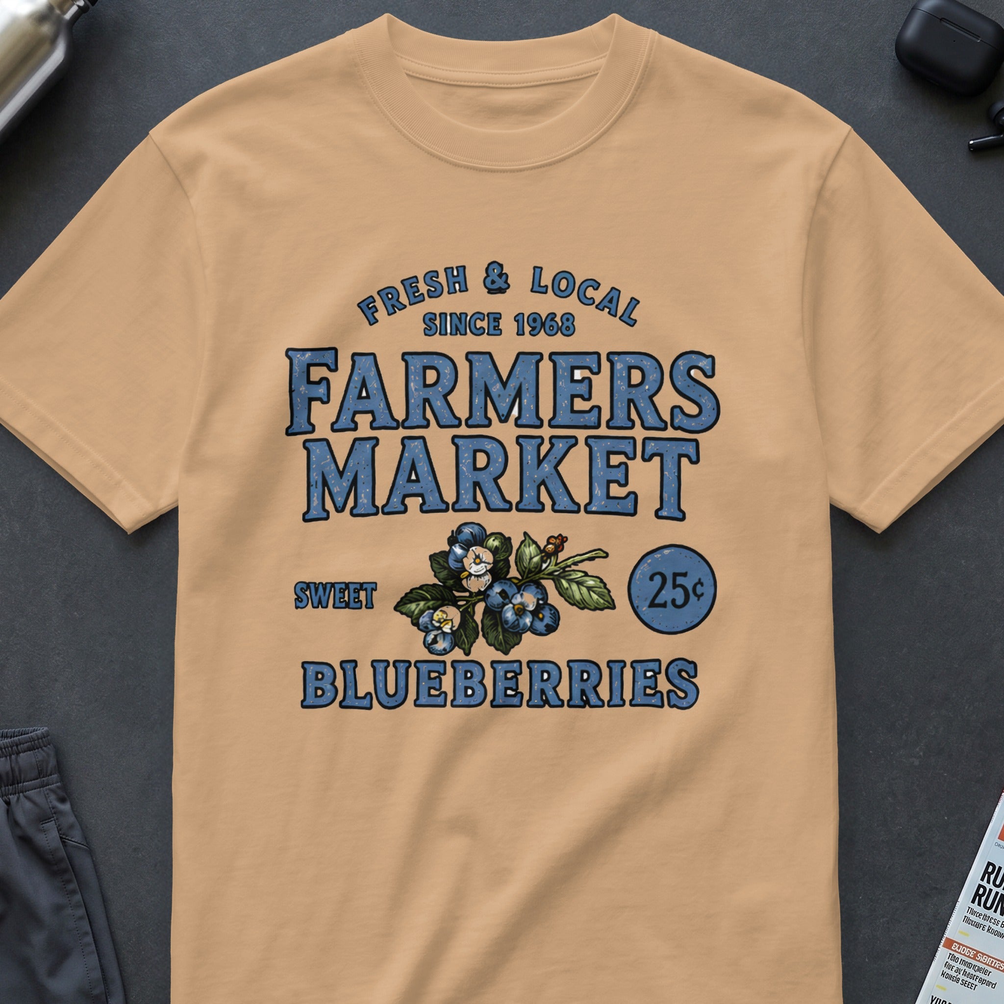 Peach t-shirt with "FRESH & LOCAL SINCE 1968 FARMERS MARKET SWEET BLUEBERRIES 25¢" text and blueberries.